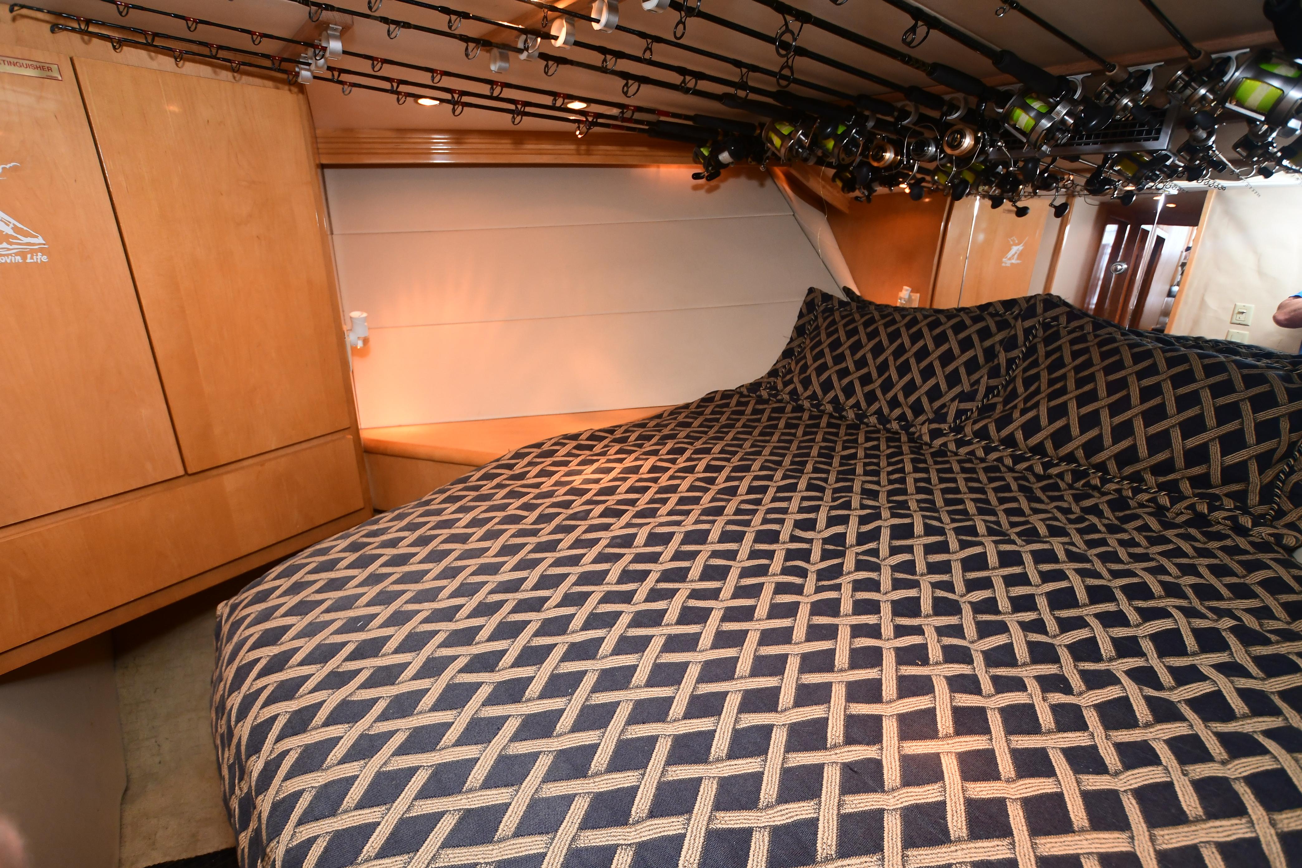 Interior of 2001 Hatteras 50 Convertible with cozy bed and fishing rods.