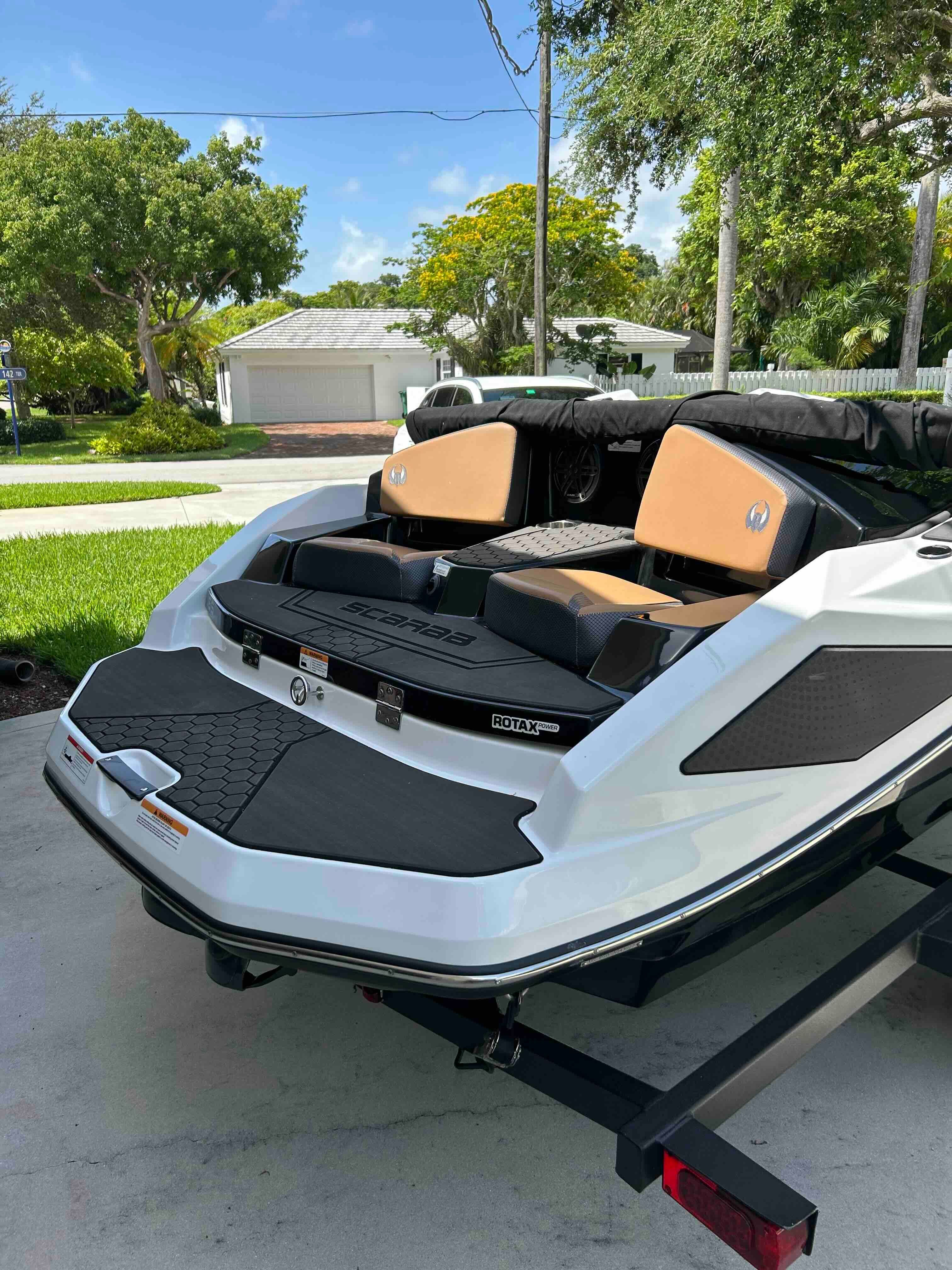 A 2022 Scarab 165 ID jet boat on a trailer in a residential area.
