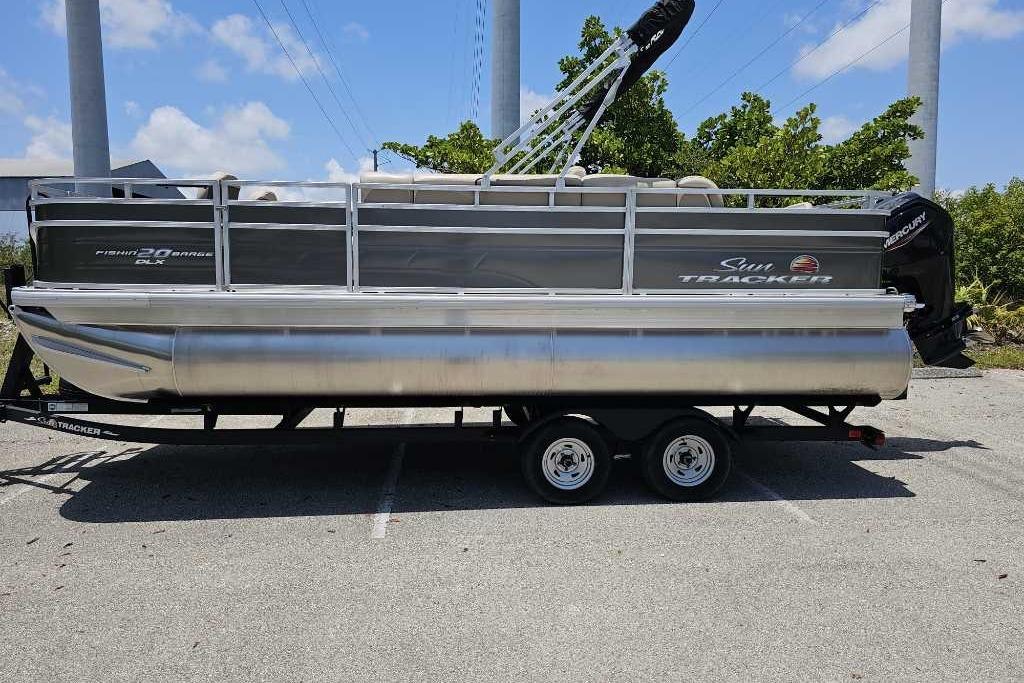 2025 Sun Tracker SportFish 20 DLX pontoon boat on trailer, parked outdoors.