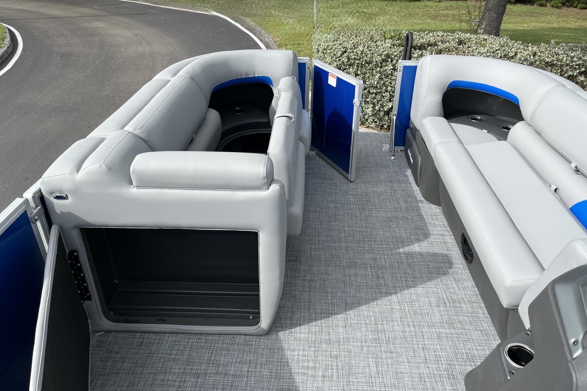 2026 Sun Tracker Party Barge 20 DLX interior with gray seating and open storage compartments.