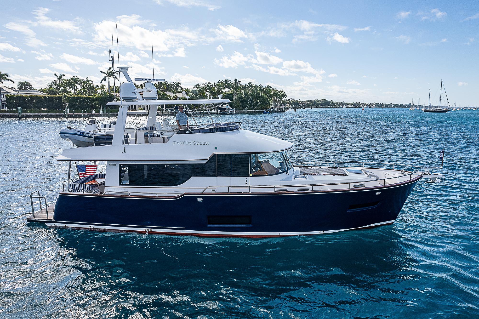 2022 Summit 54 Motoryacht cruising on a sunny day, with clear blue water and sky.