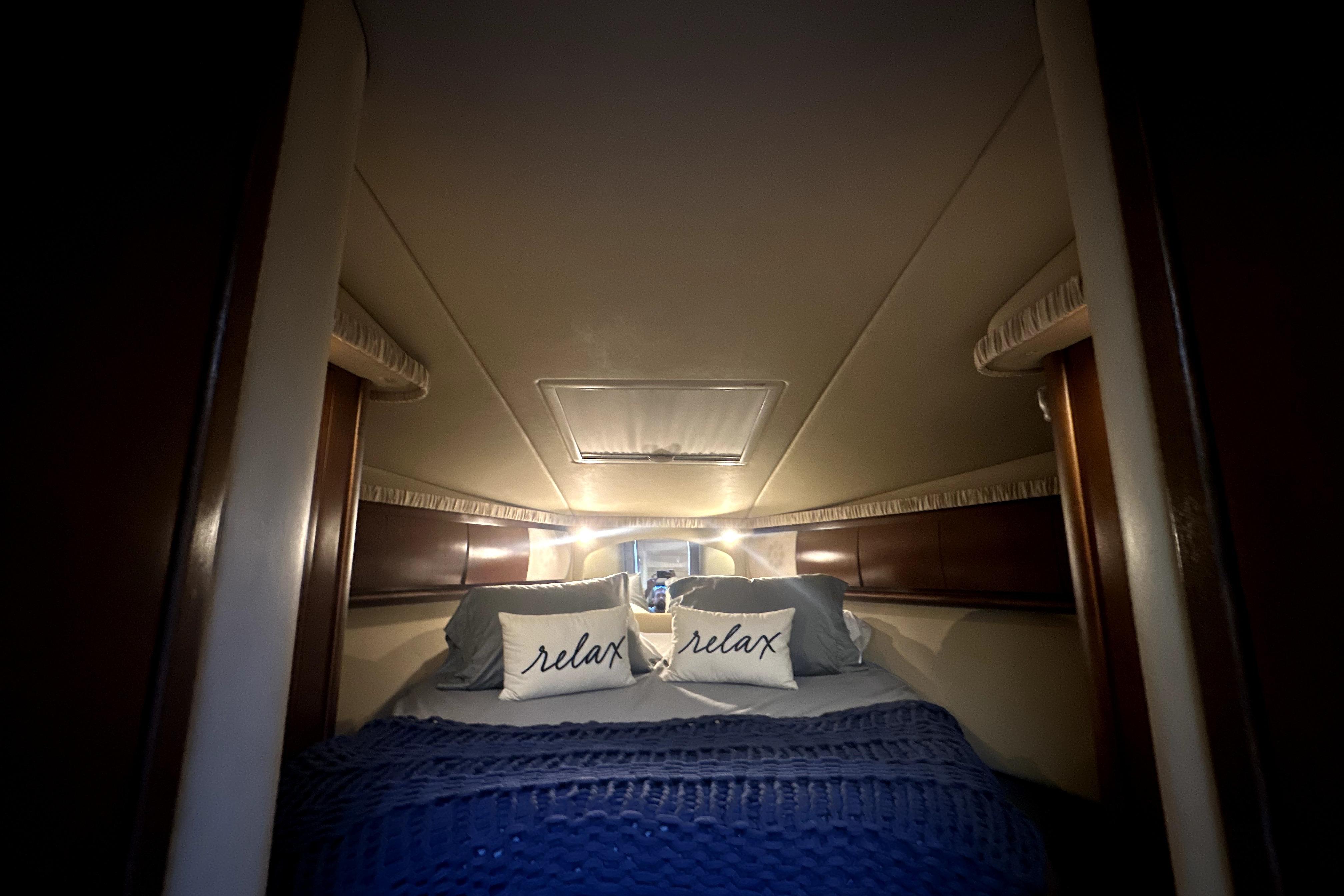 Luxurious cabin interior of 2007 Sea Ray 44 Sundancer with cozy bedding and ambient lighting.