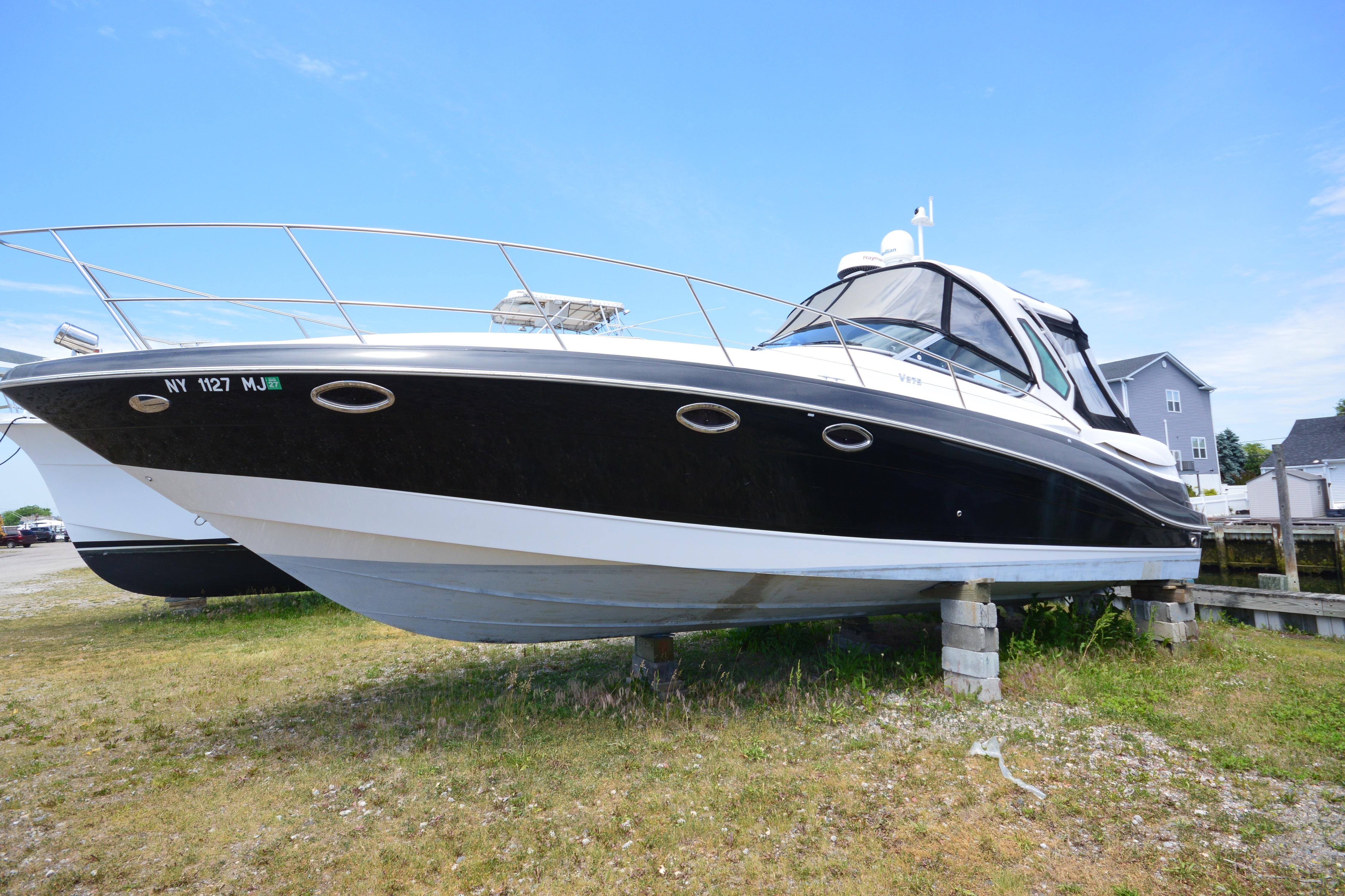 2013 Four Winns V375 boat on land, black and white exterior, clear sky background.