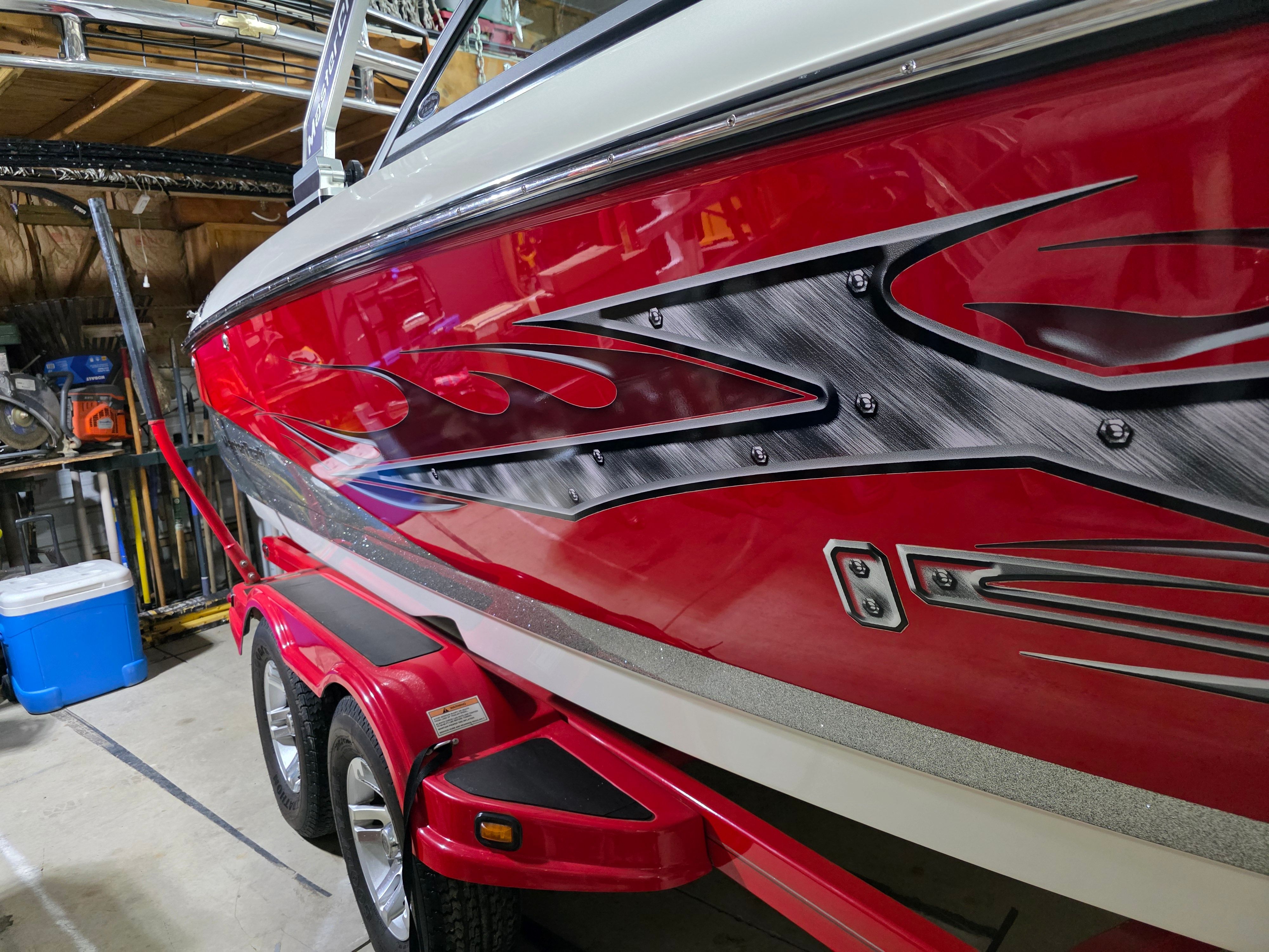 2007 MasterCraft X-15 boat with red flame design in garage.