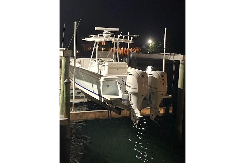 2002 Intrepid 323 Cuddy boat docked at night with dual outboard engines.