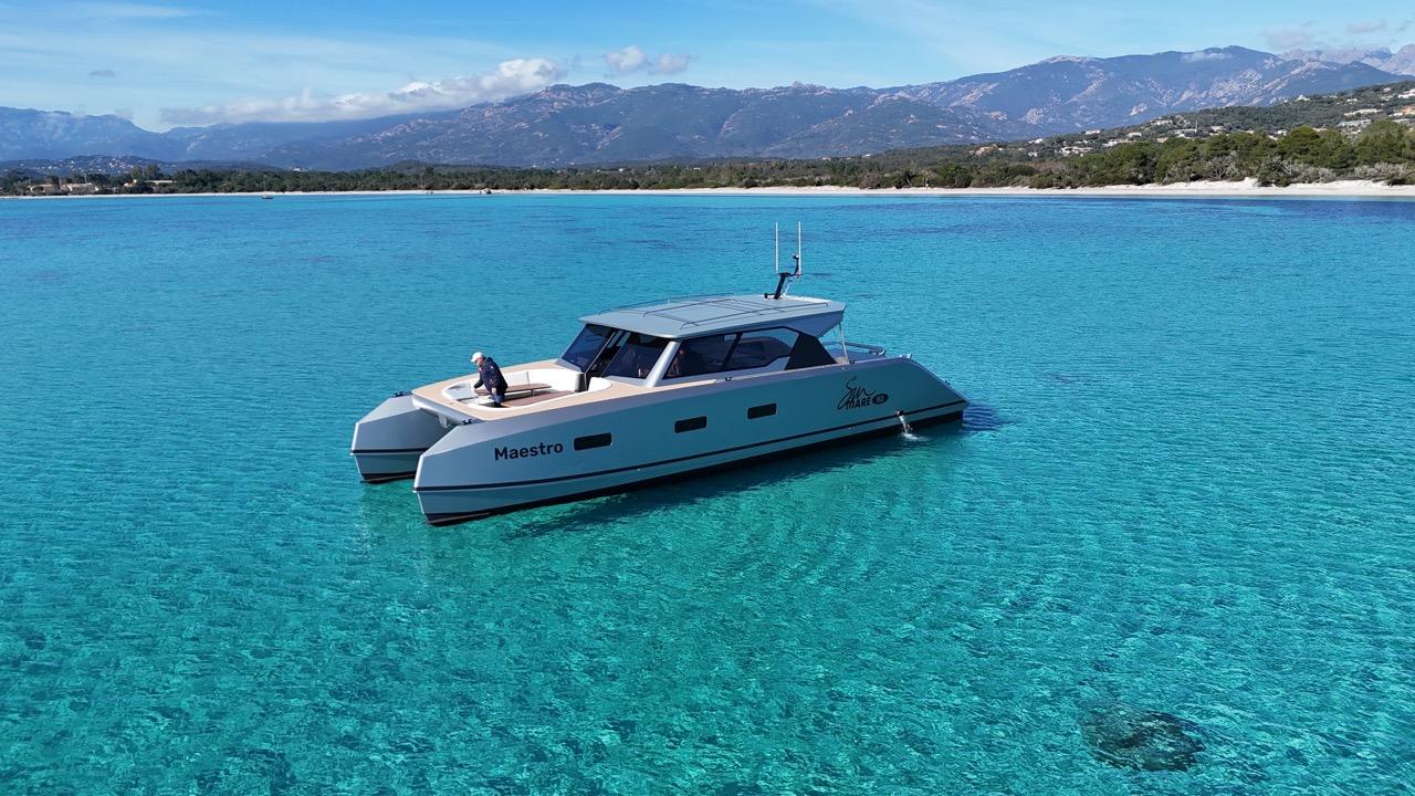 2024 Sunmare 50 Hybrid Catamaran on clear turquoise water with scenic mountain backdrop.