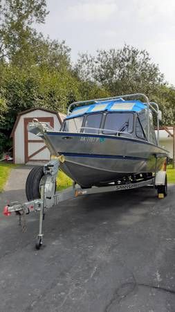 A Hewescraft Sea Runner 210 boat on a trailer in a driveway.