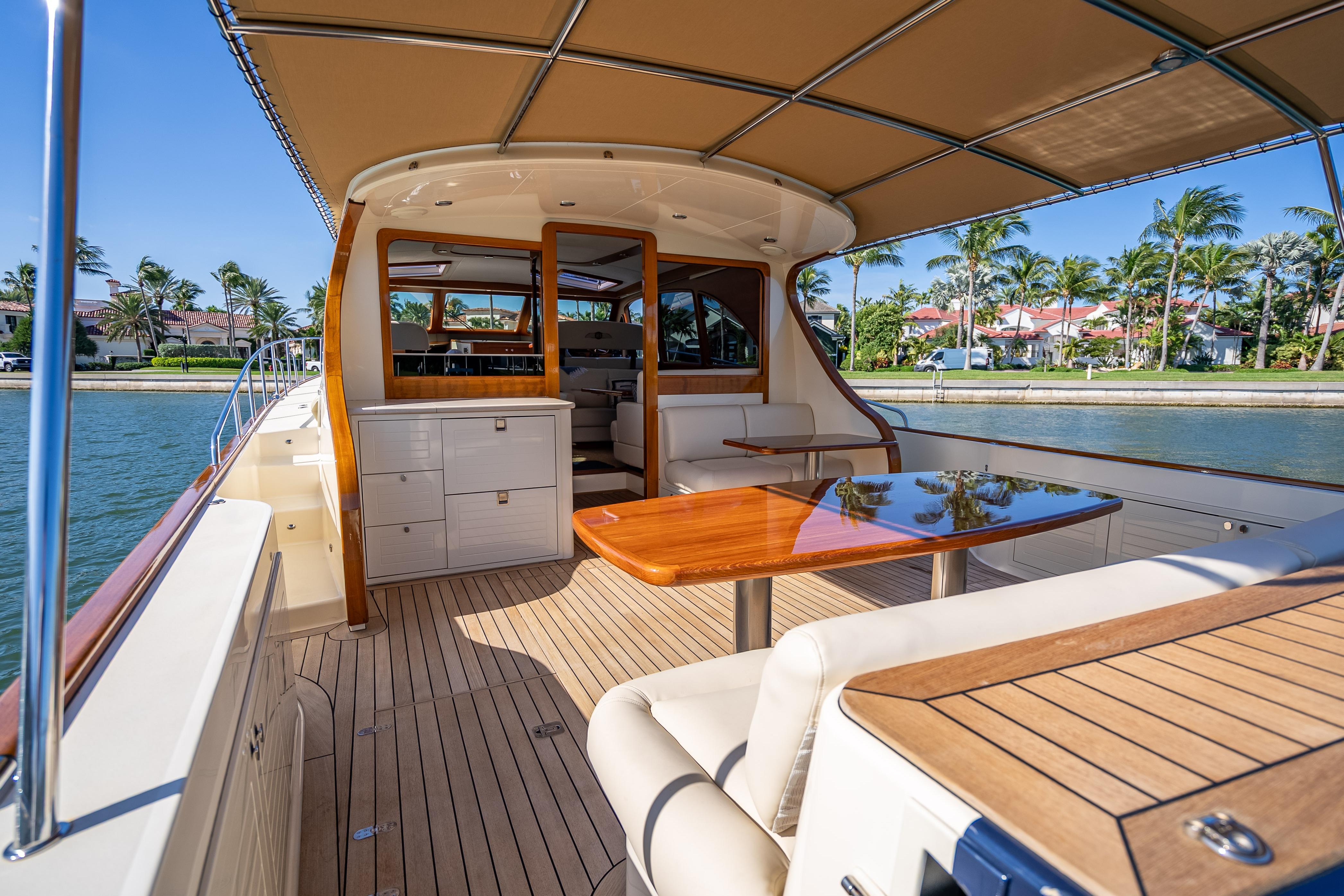2018 Palm Beach Motor Yachts PB55, luxurious deck with elegant seating and table, waterfront view.