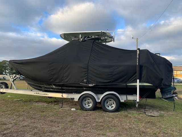 A 2018 Sportsman Heritage 241 Center Console boat on a trailer, covered with a black tarp.