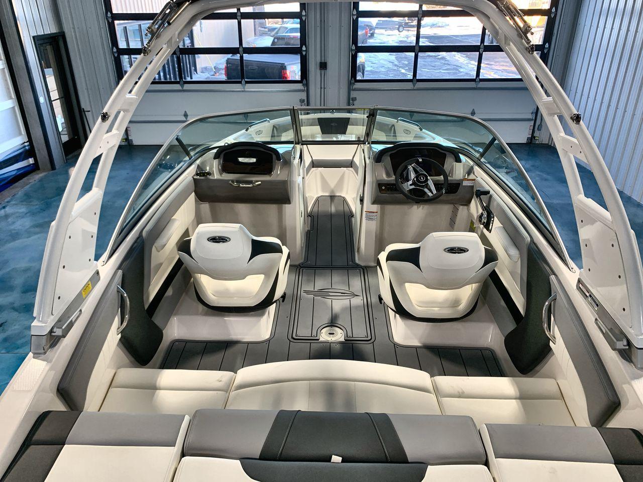 2025 Chaparral 21 SSi boat interior with modern seating and steering wheel in showroom.