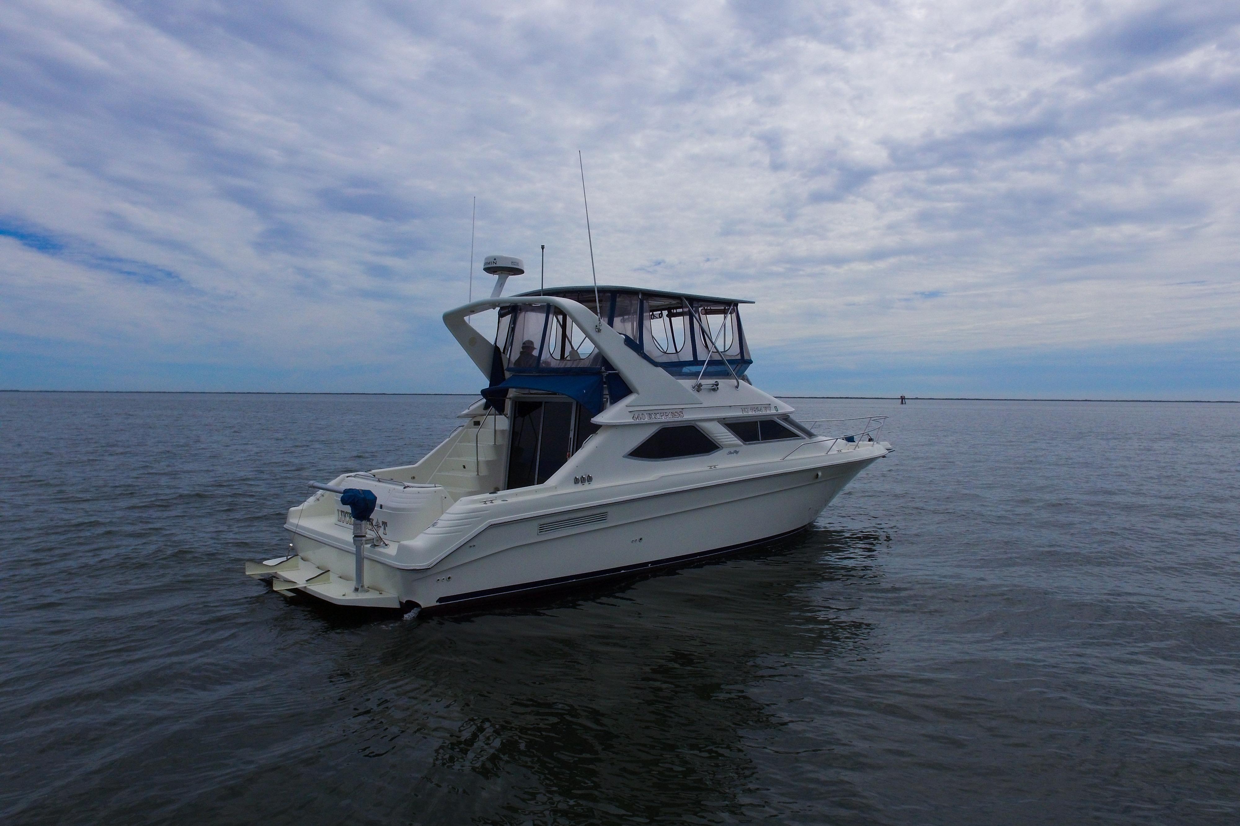 1993 Sea Ray 440 Express Bridge yacht on calm waters under a cloudy sky.