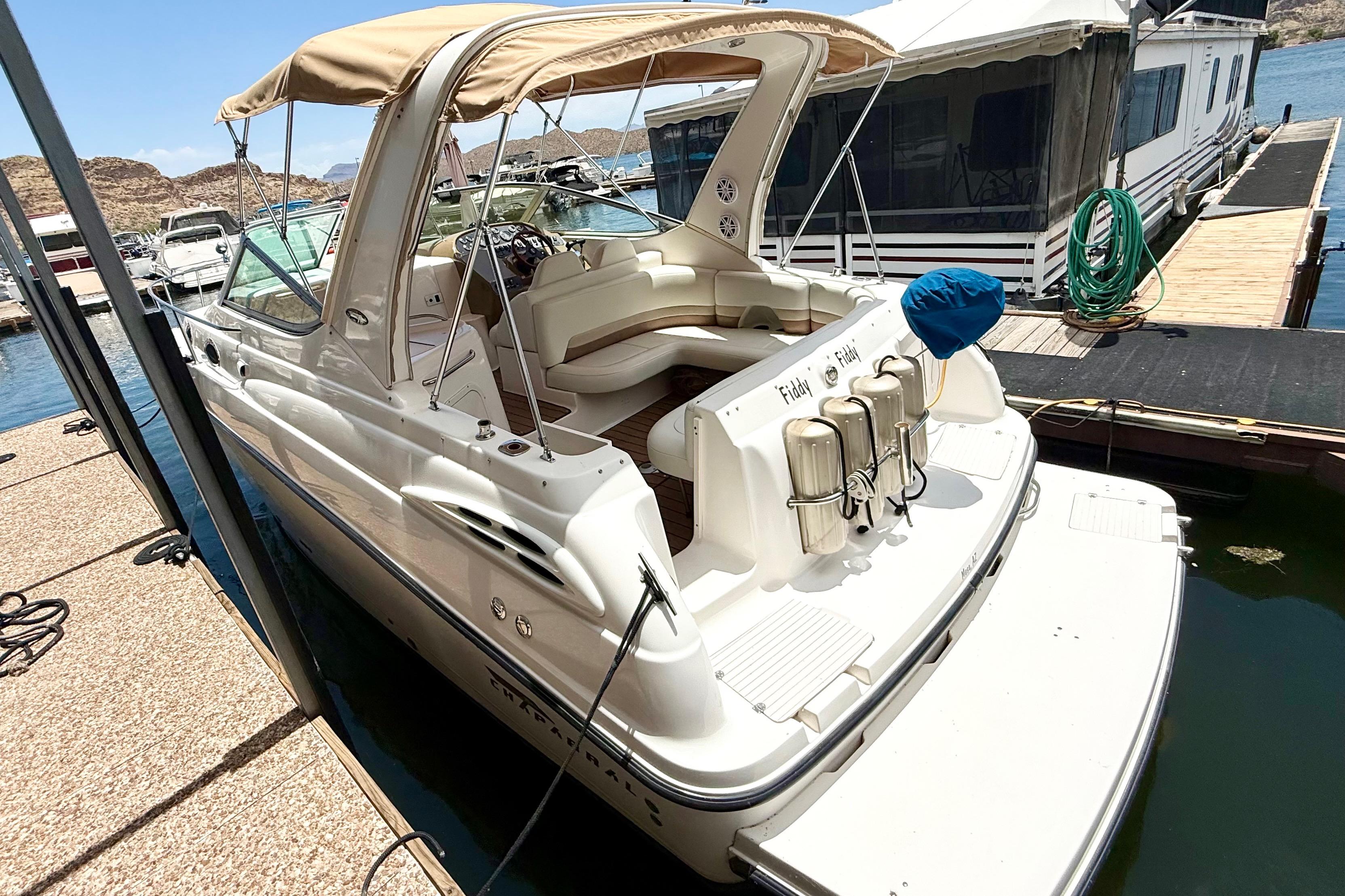1999 Chaparral Signature 300 boat docked at marina, featuring beige canopy and spacious seating.