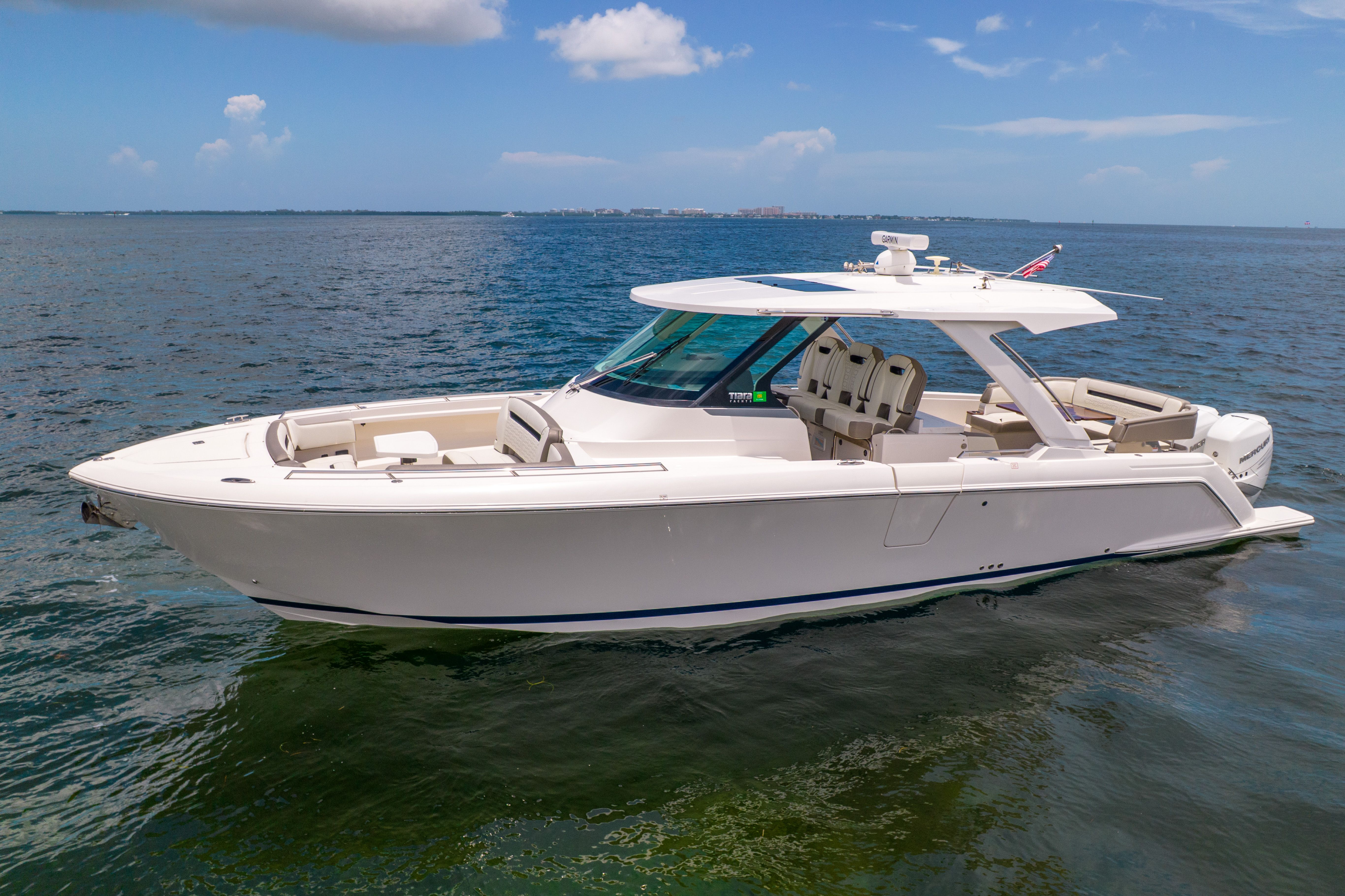The 2023 Tiara Yachts 38 LS is a sleek motorboat on calm water under a blue sky.