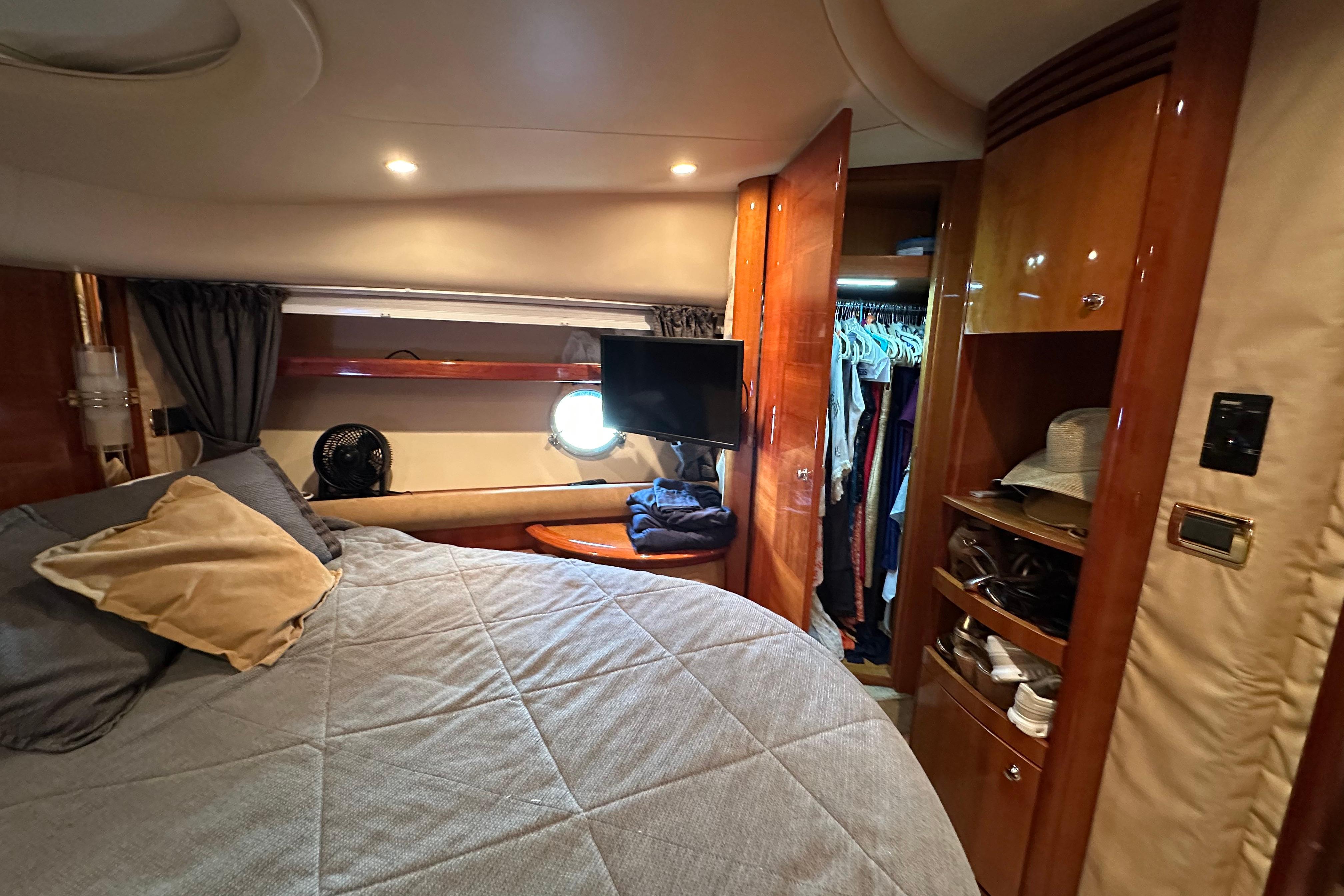 Luxurious 2004 Azimut 55E yacht bedroom with cozy bedding and elegant wood finishes.