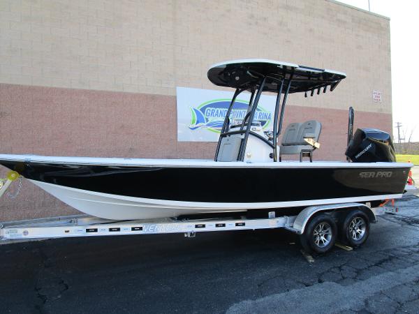 2025 Sea Pro 230 Bay boat on trailer, black hull, parked at marina.