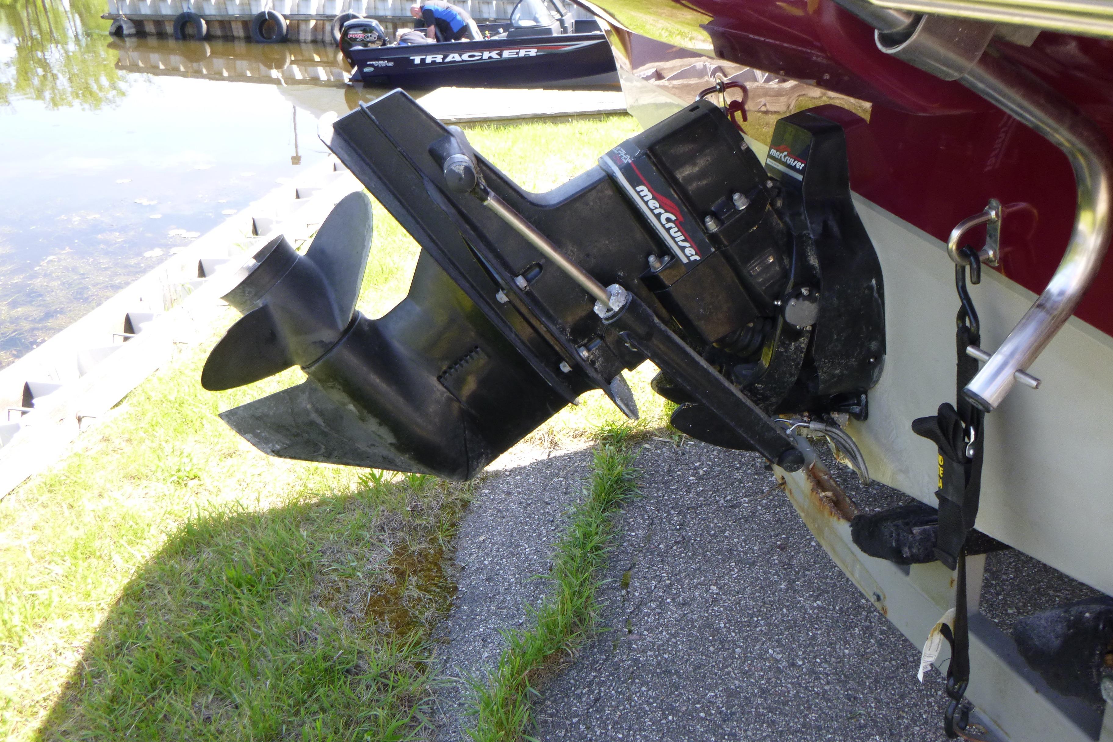 Outboard motor of a 1998 Maxum 2300 SC boat near a lakeside dock.