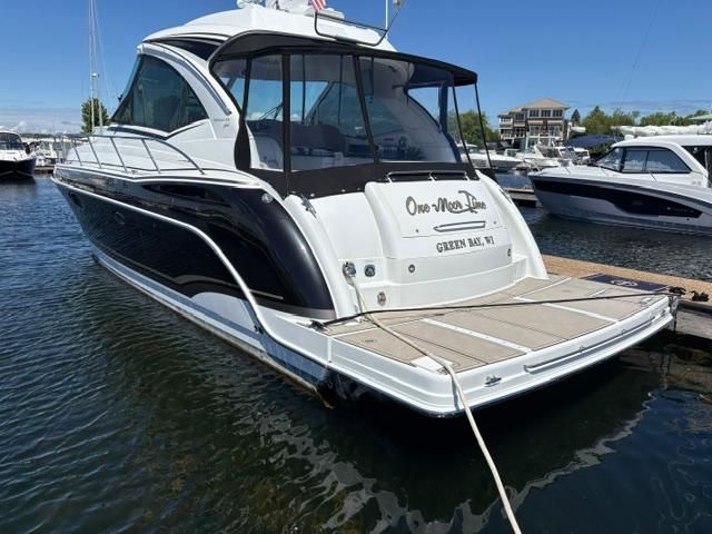 An elegant motor yacht with a black hull and white deck, docked at a marina.