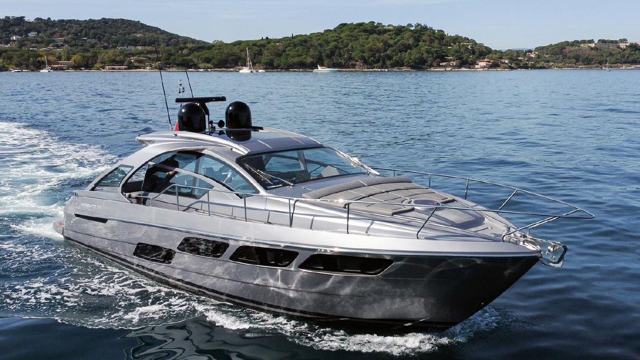 2018 Pershing 5x yacht cruising on a serene blue sea near a lush green coastline.