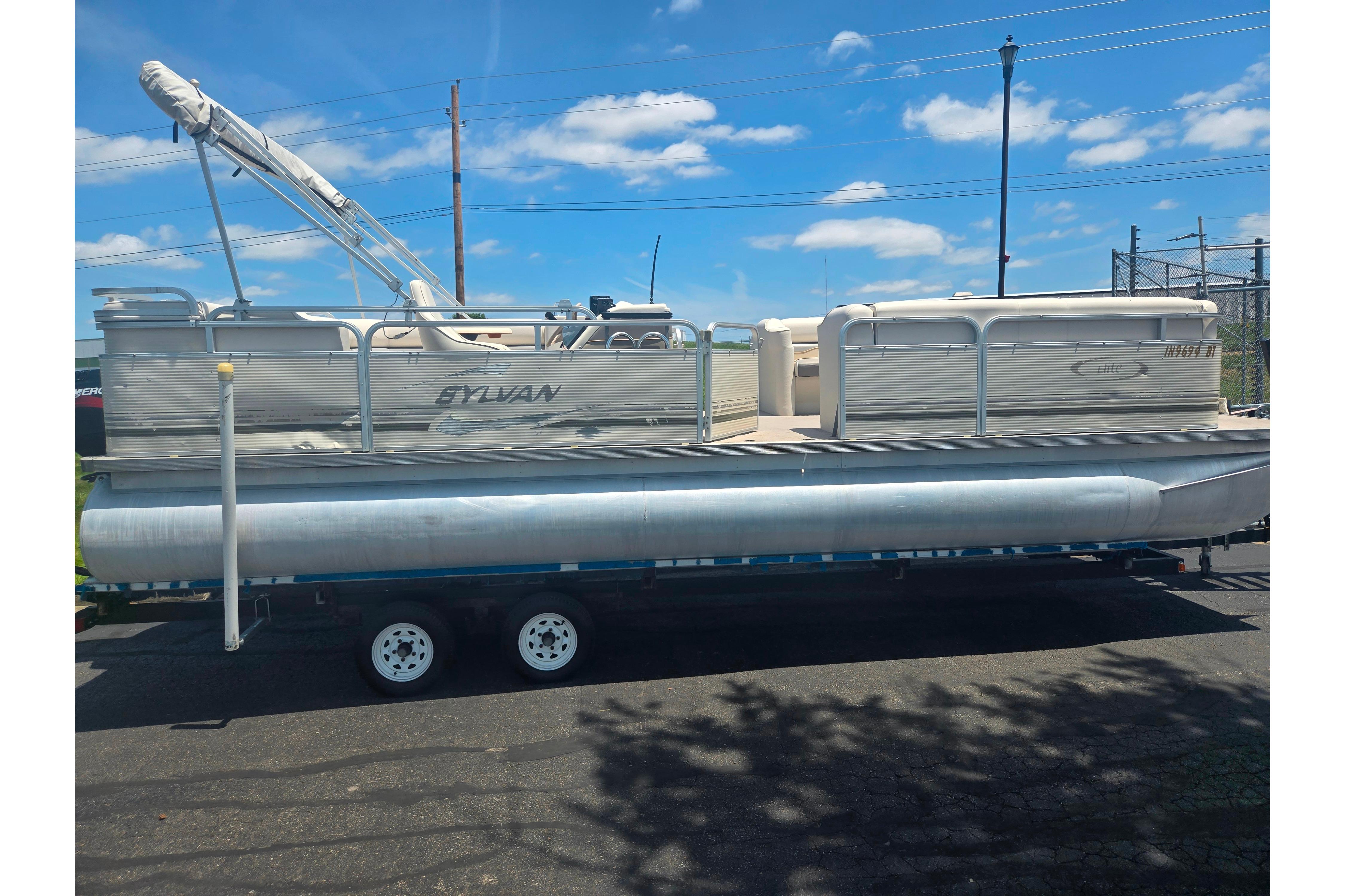 2000 Sylvan 824 Elite Cruise pontoon boat on trailer under blue sky.