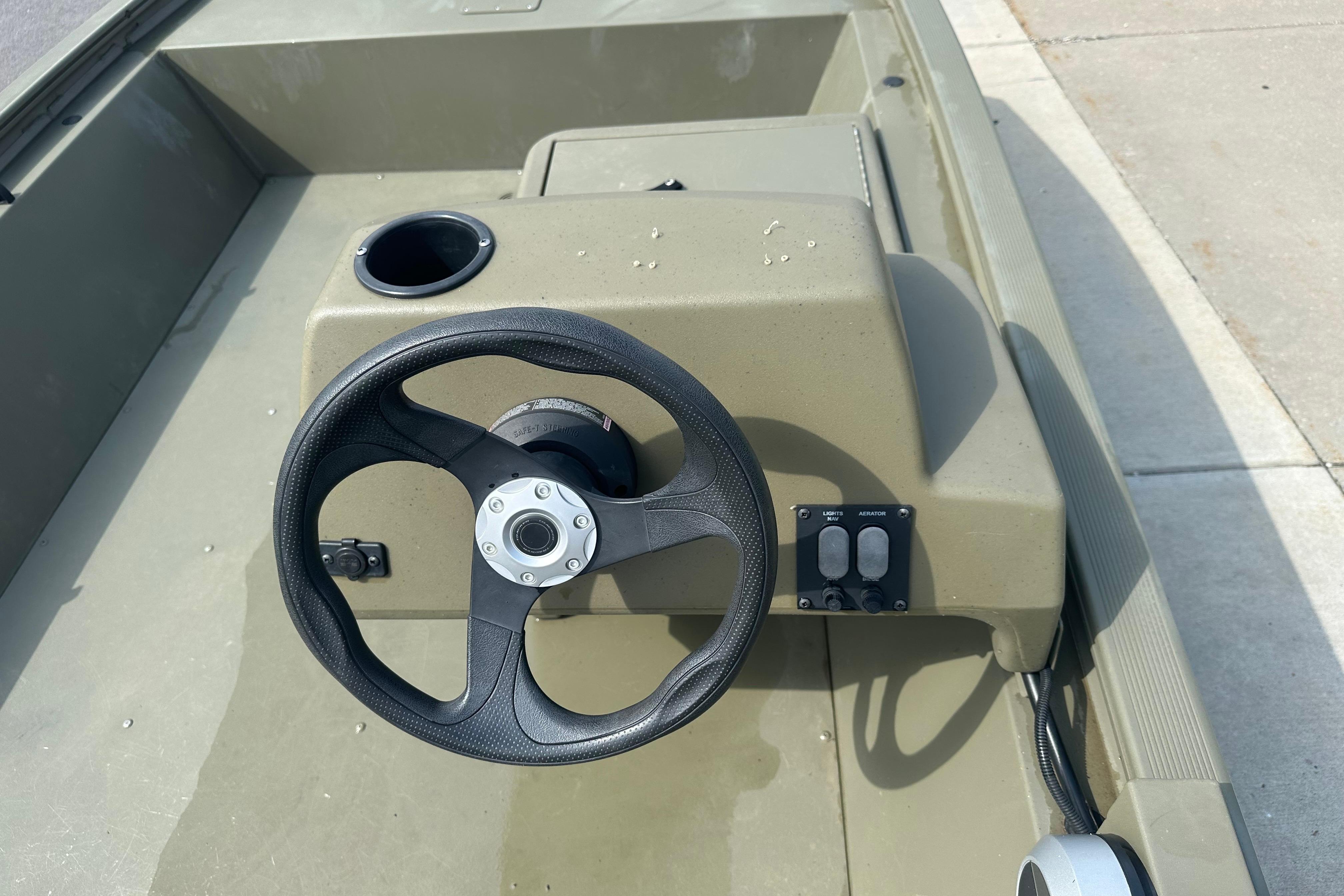 Steering console of 2024 Tracker Grizzly 1648 SC boat with cup holder and controls.
