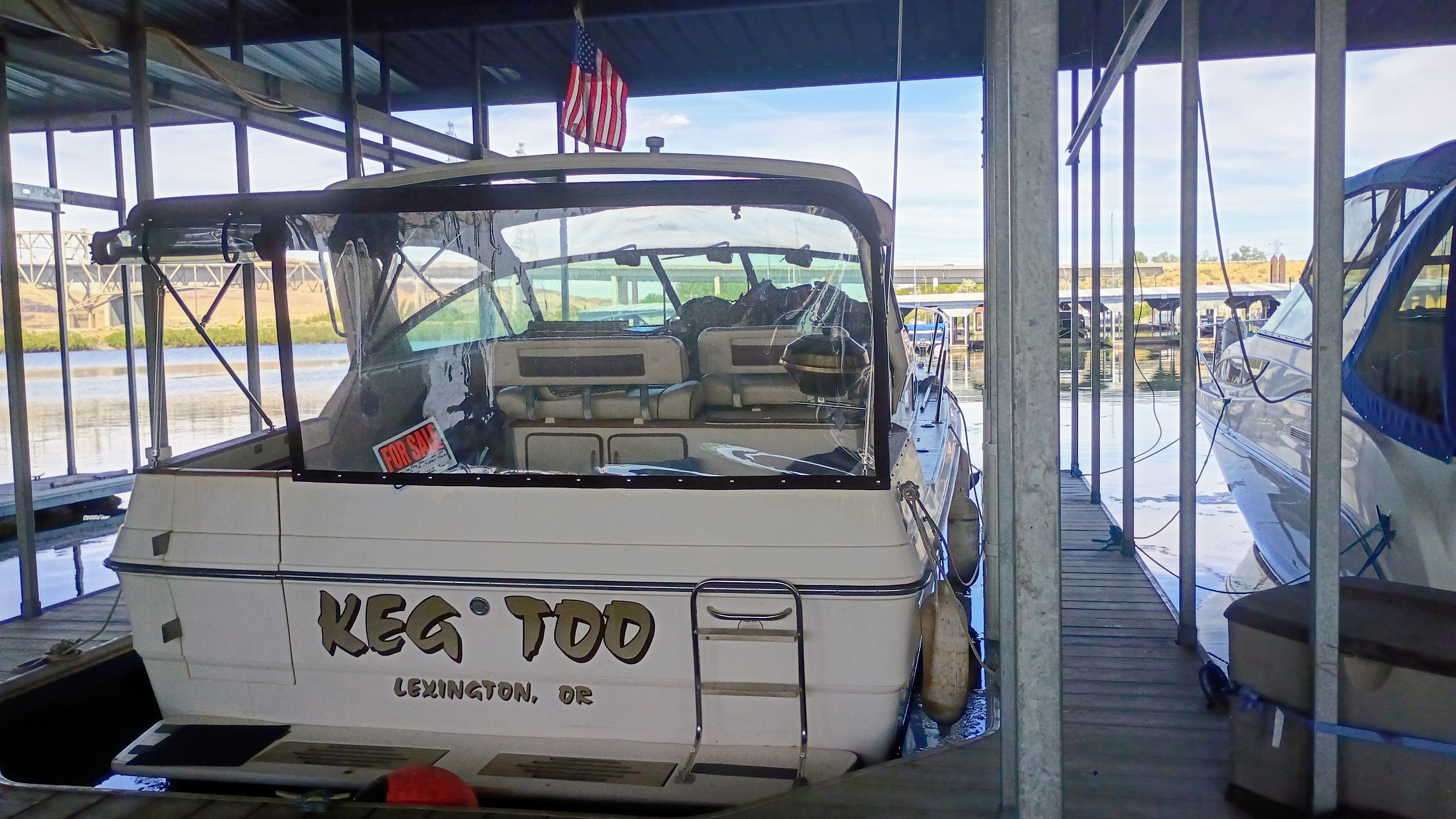 A 1986 Sea Ray Sundancer docked in a covered slip. The back displays the name "KEG TOO."