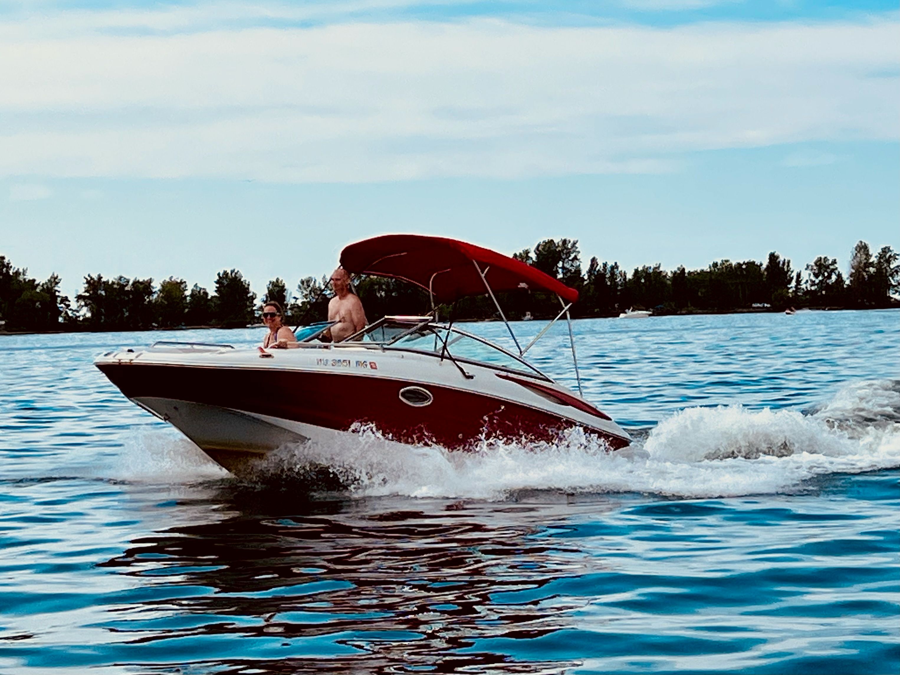 2009 Crownline 220 EX on the water with a red sunshade.