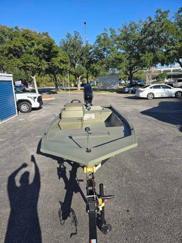 2025 Tracker Grizzly 1648 SC boat in parking lot, surrounded by trees and cars.