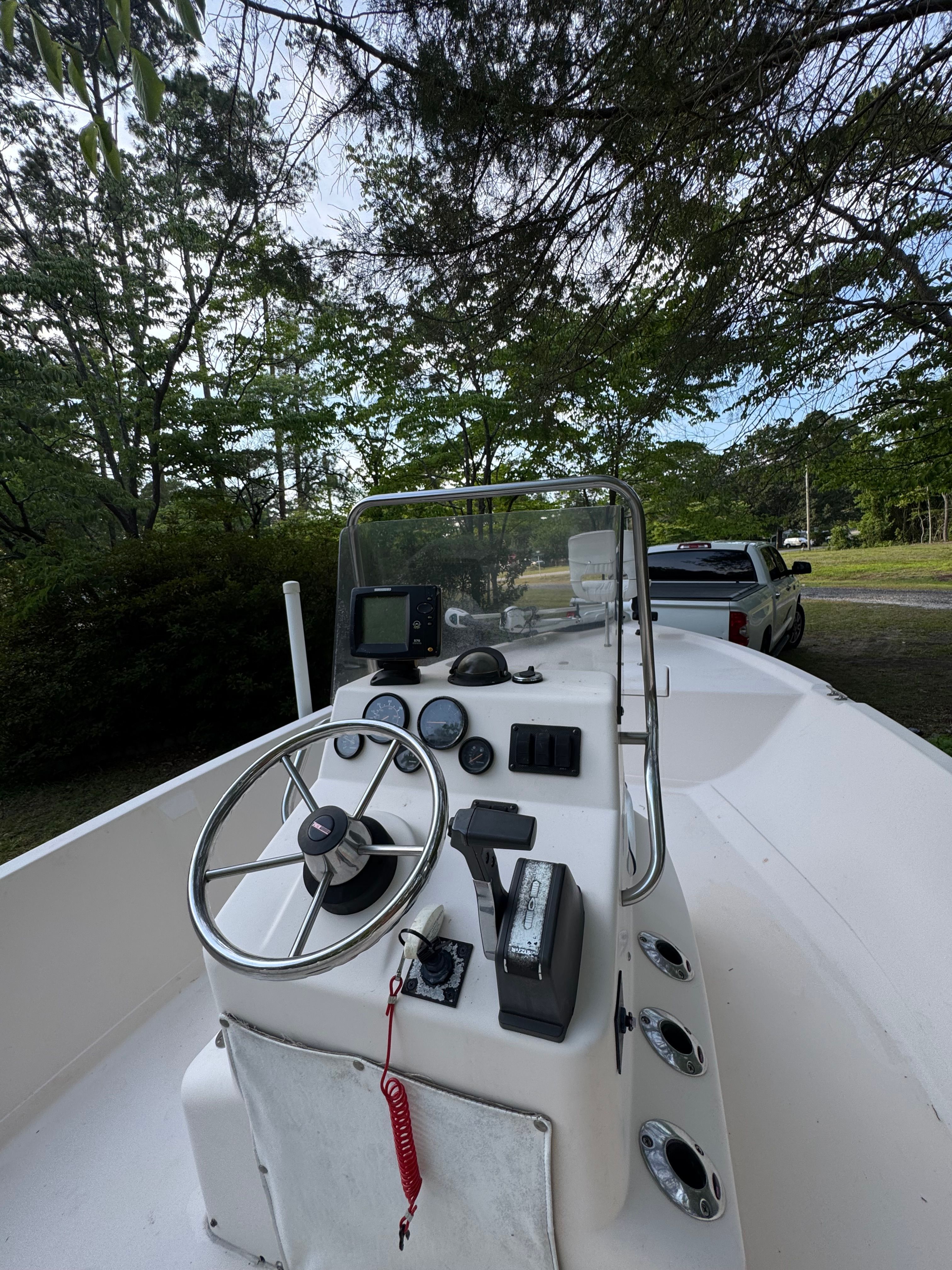 The image shows a boat's helm with a steering wheel and instruments.