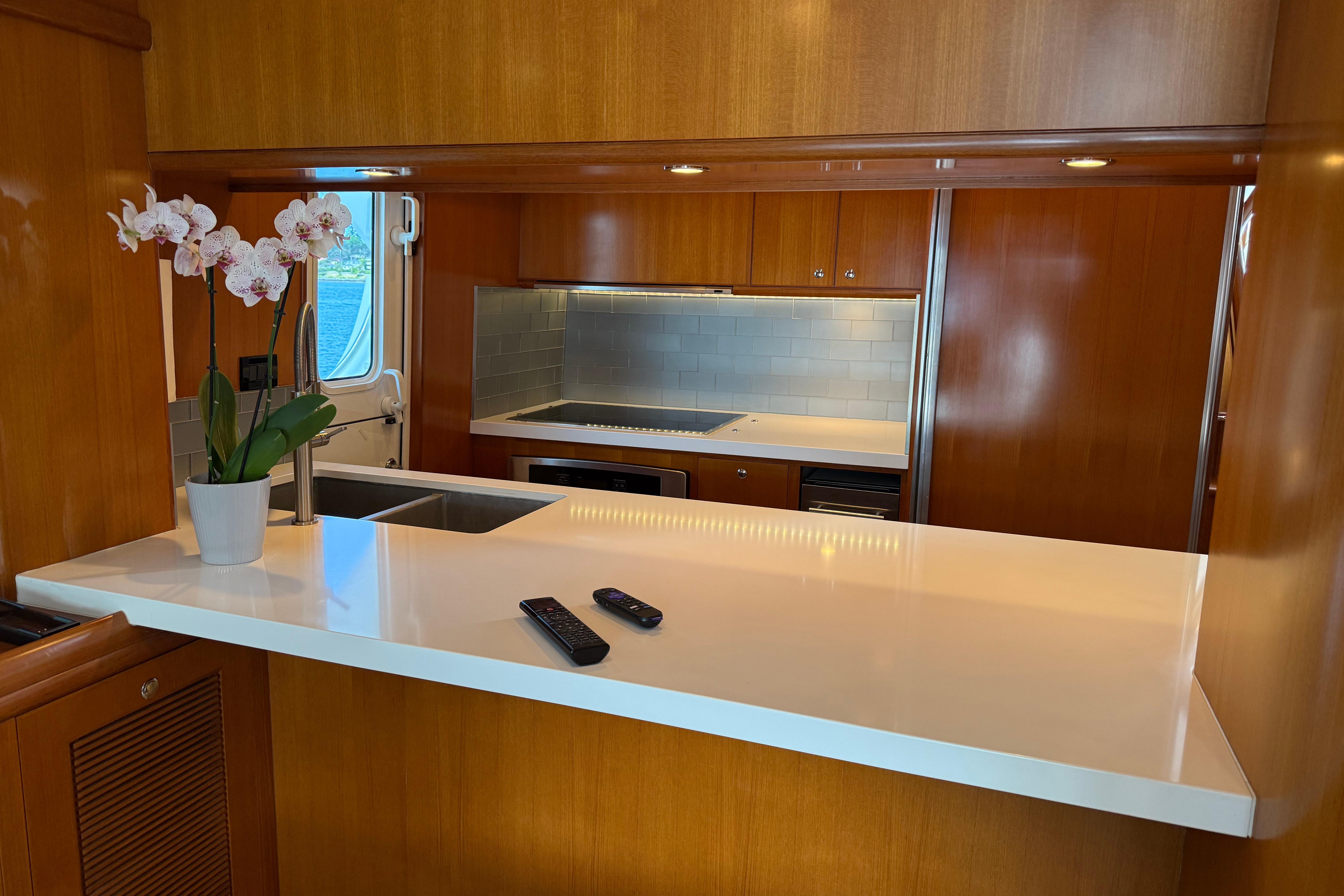 Luxurious 2009 Nordhavn N64 yacht kitchen with sleek countertops and elegant wood cabinetry.