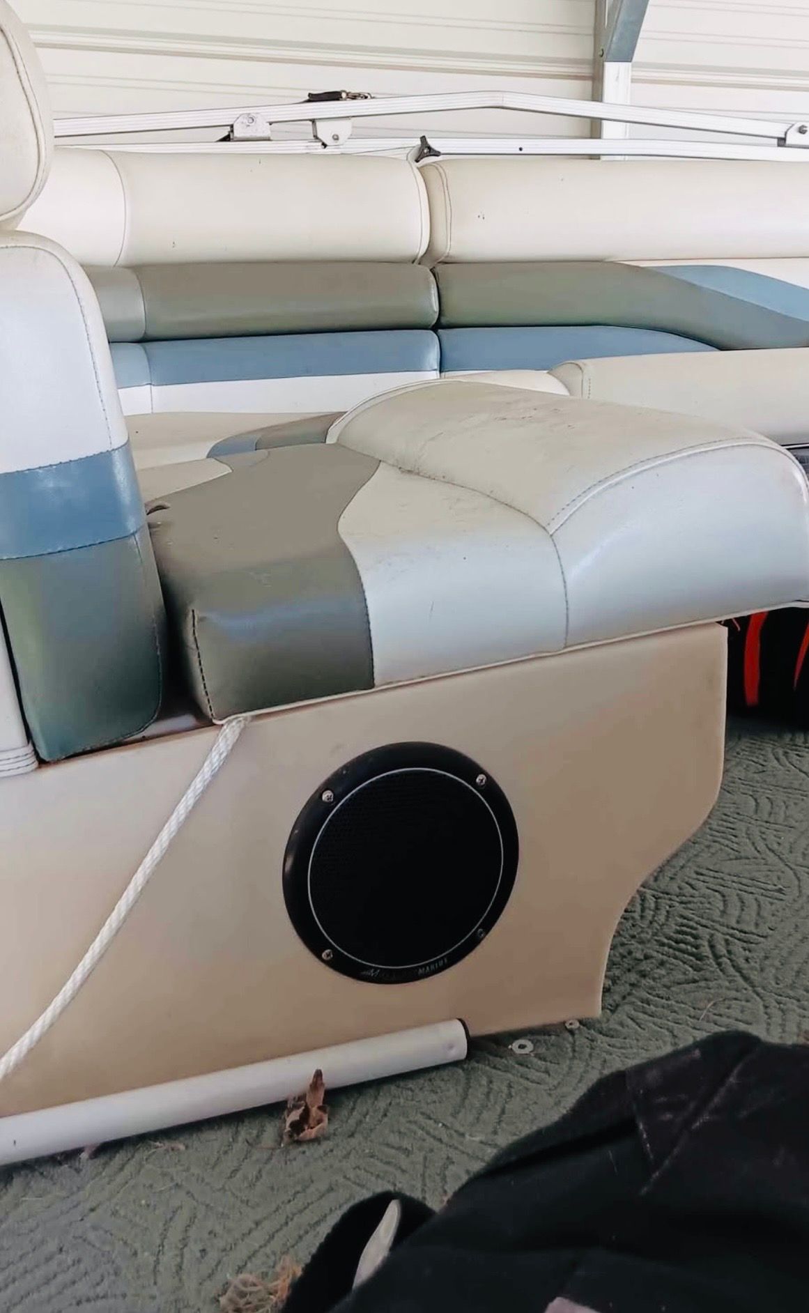 Interior view of a boat with cushioned seats and a speaker.
