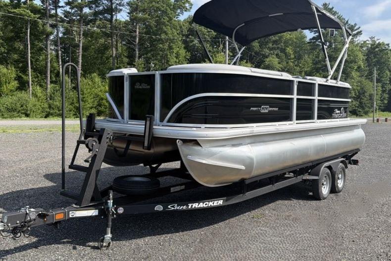 2026 Sun Tracker Party Barge 20 DLX pontoon boat on trailer, parked outdoors.