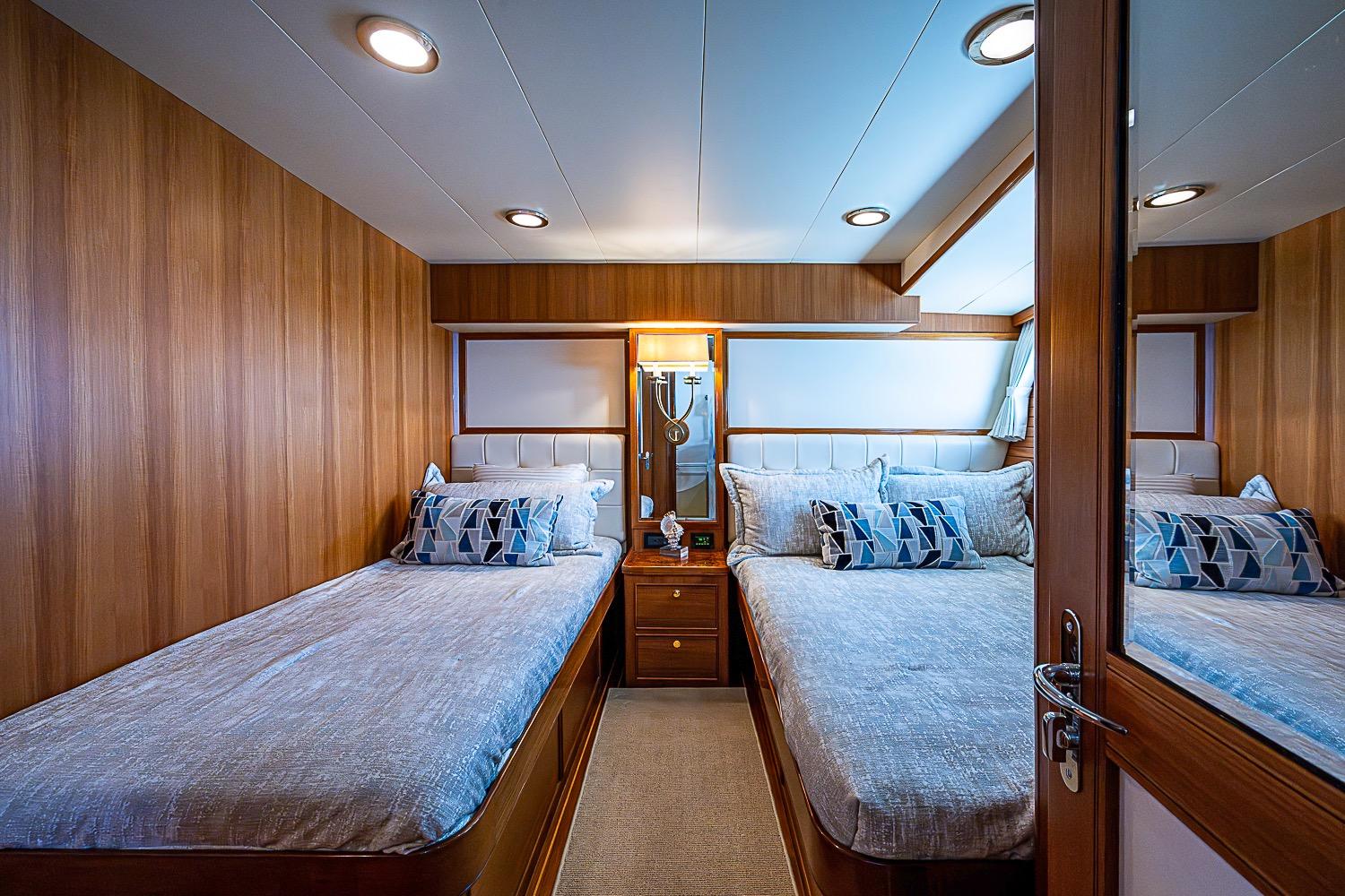 Luxurious cabin interior of 2014 Marlow 80 Explorer yacht with twin beds and elegant wood paneling.