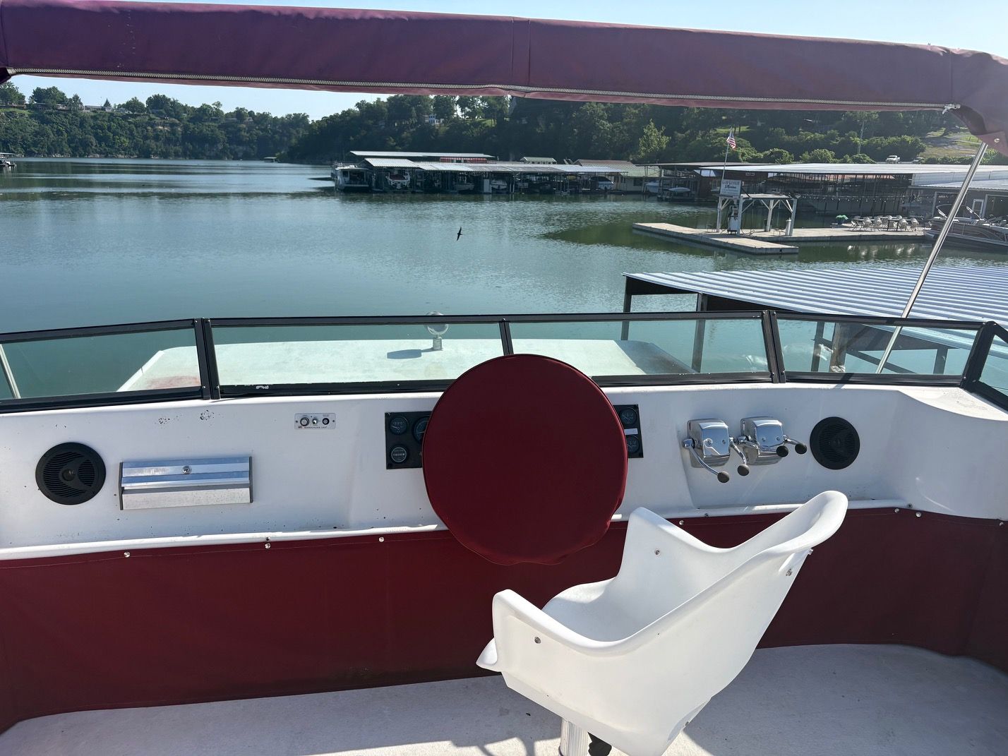 The helm of a 1989 Sumerset houseboat overlooking a calm lake.