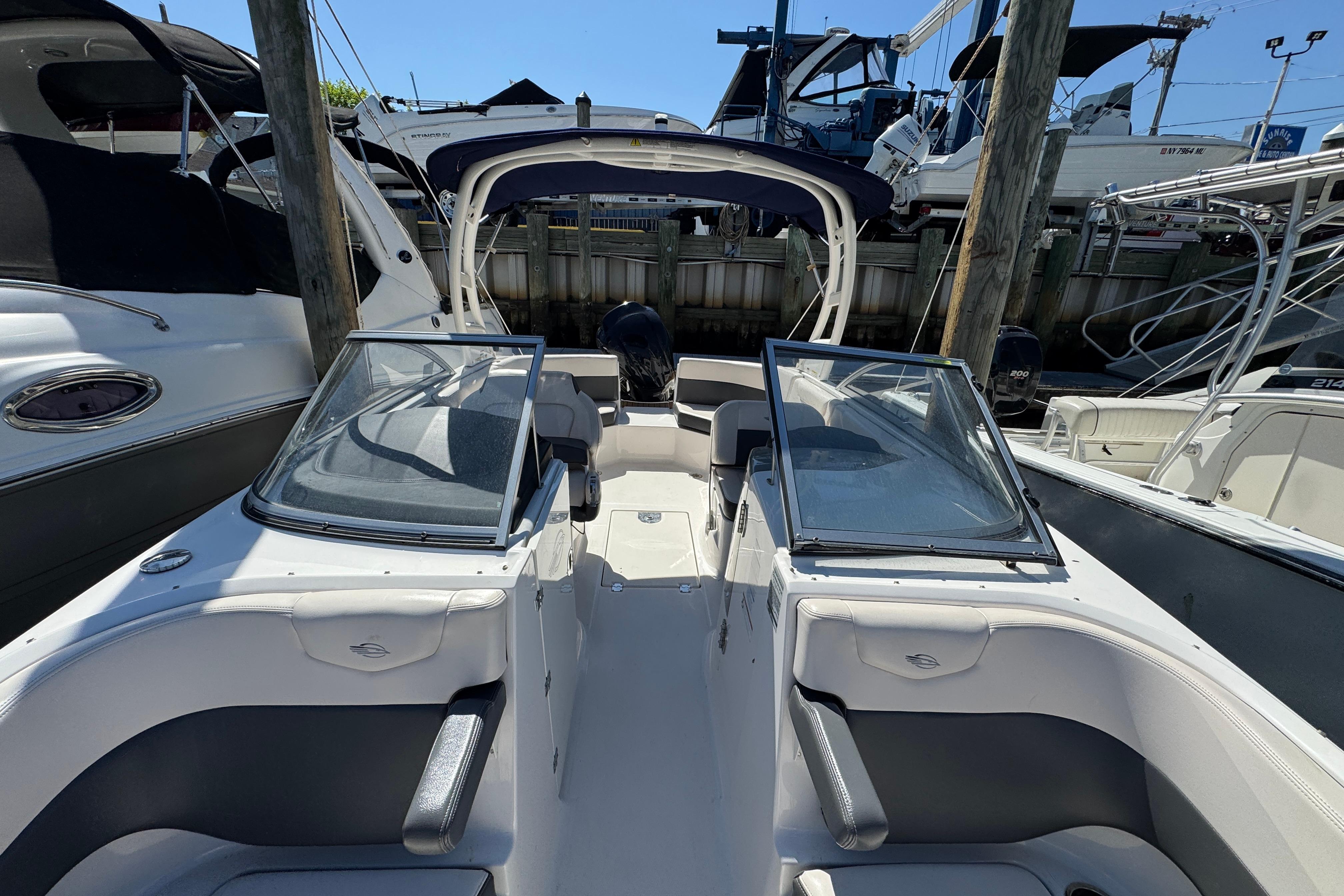 2018 Chaparral 250 Suncoast boat docked, featuring dual windshields and spacious seating.