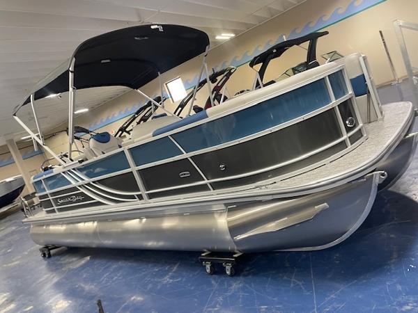 2025 South Bay LE pontoon boat in showroom, featuring sleek design and blue accents.
