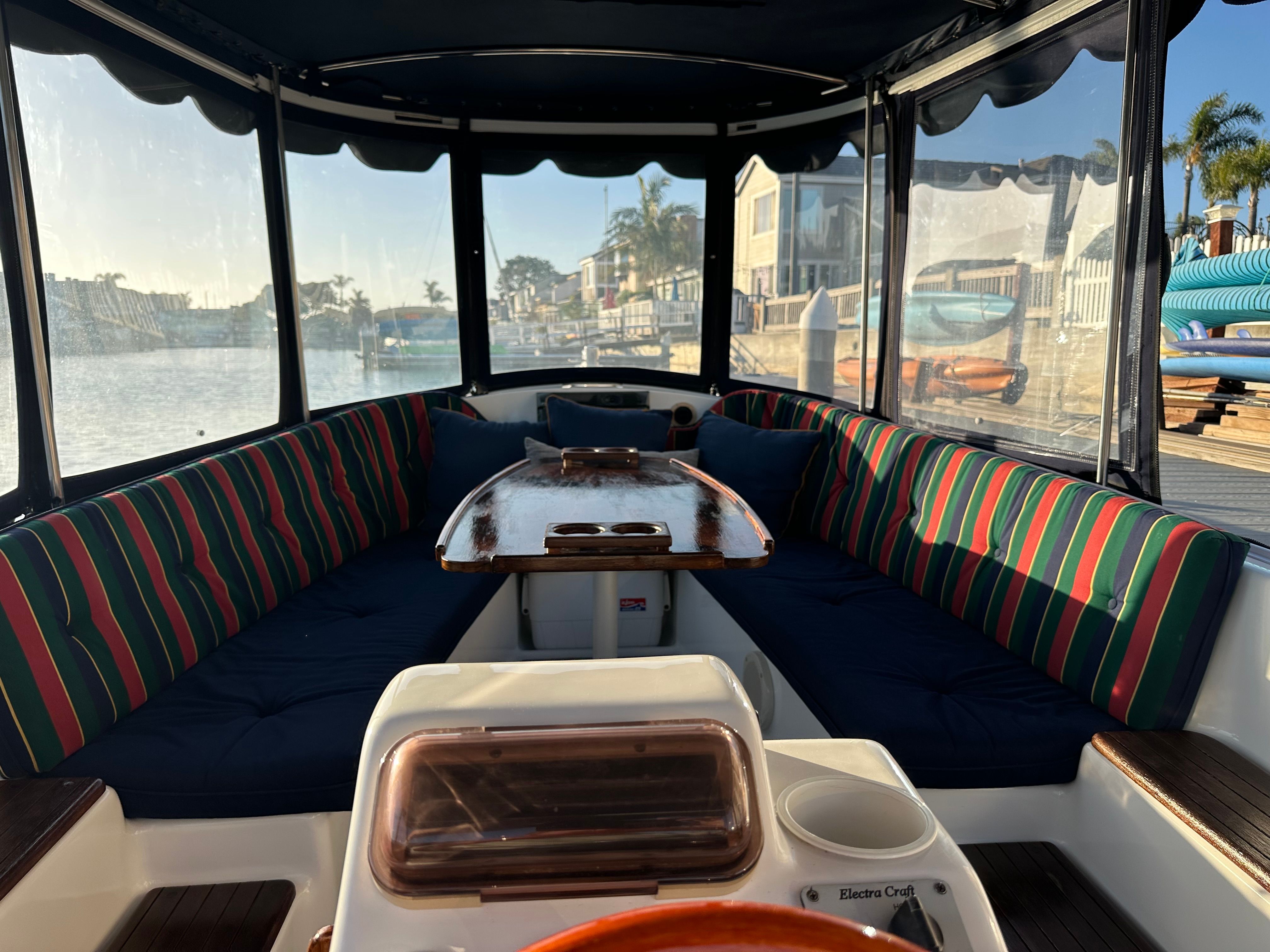 Interior of a 2004 ElectraCraft 18LS with striped cushions and a wooden table.