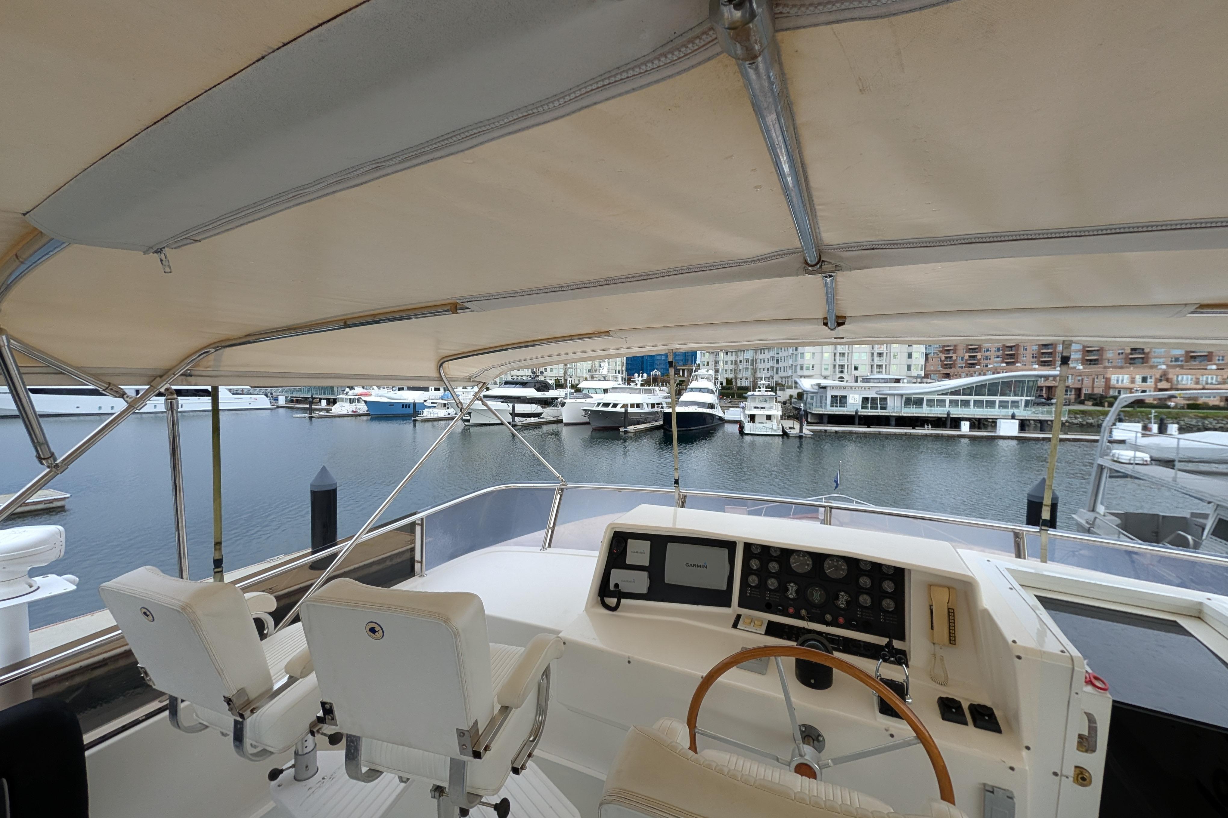 Helm of 1996 Symbol 75 yacht with marina view, featuring dual seats and control panel.