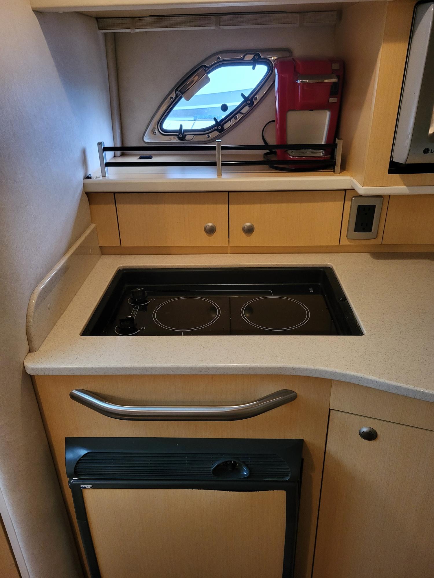 Compact kitchen area in 2009 Sea Ray 310 Sundancer yacht with stove and window.