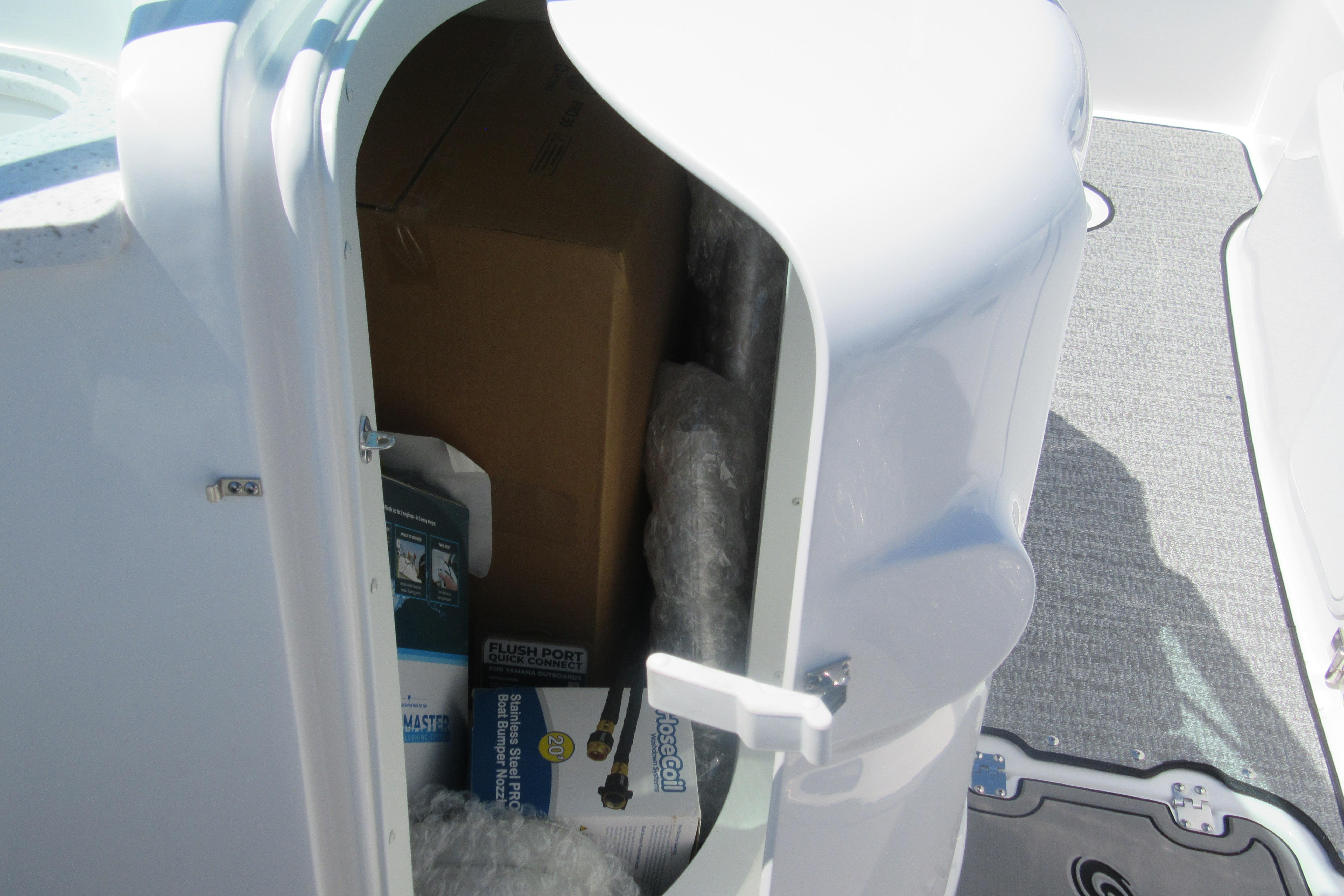 Storage compartment on 2027 Hurricane SunDeck 2486 OB boat, containing various items.