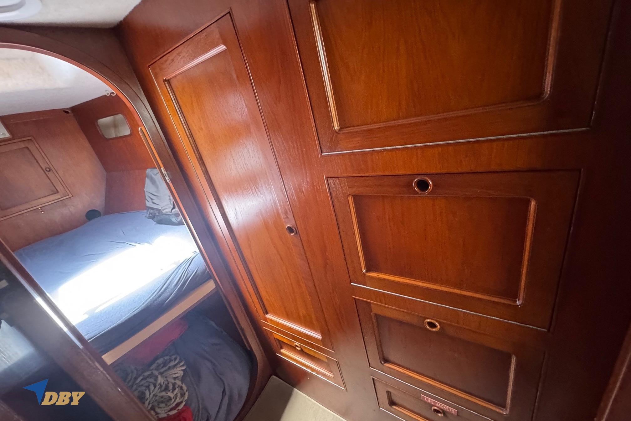 Interior of 1987 Bowman 47 yacht with wooden cabinetry and cozy sleeping area.