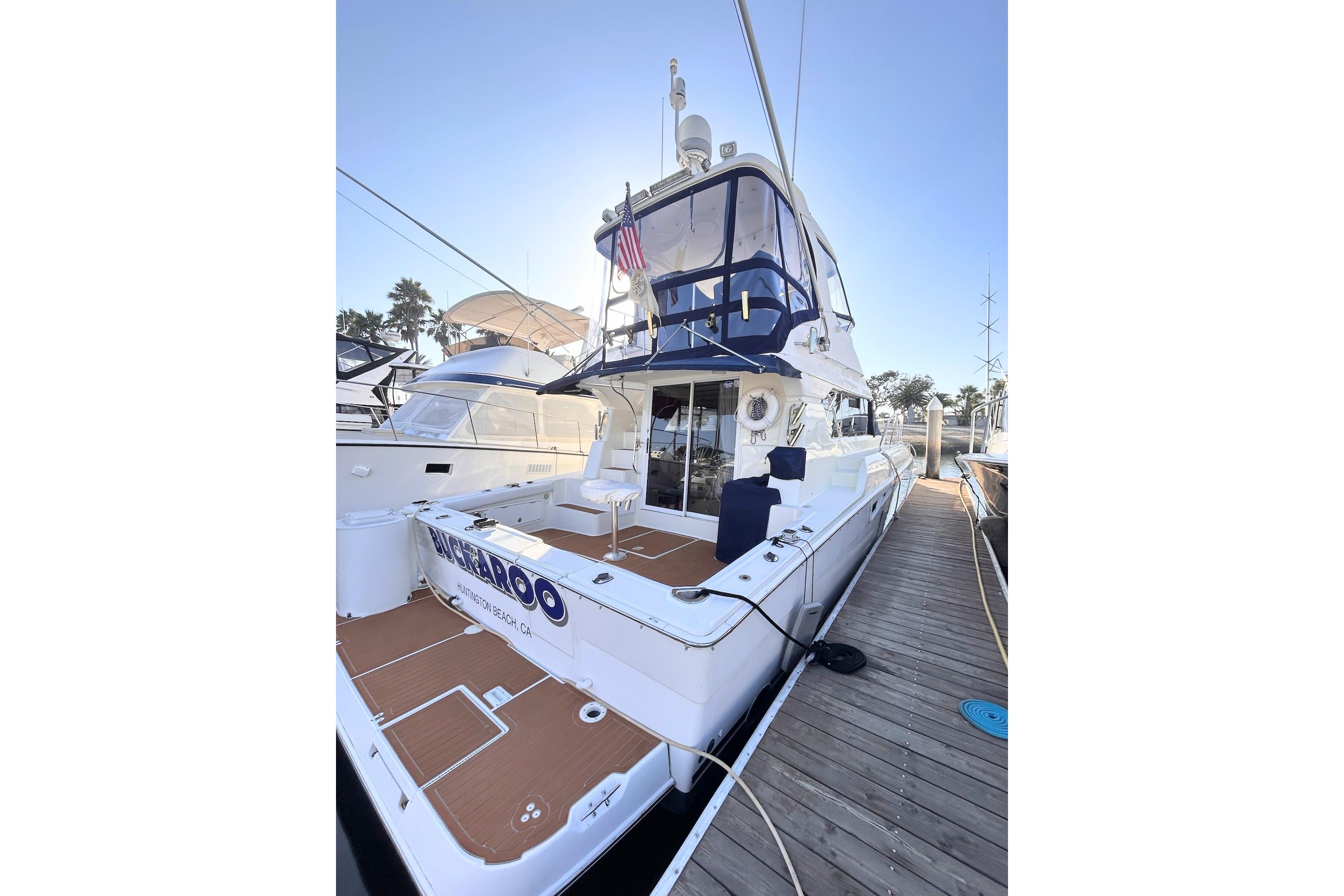 2000 Silverton 42 Convertible yacht docked, featuring spacious deck and sleek design.