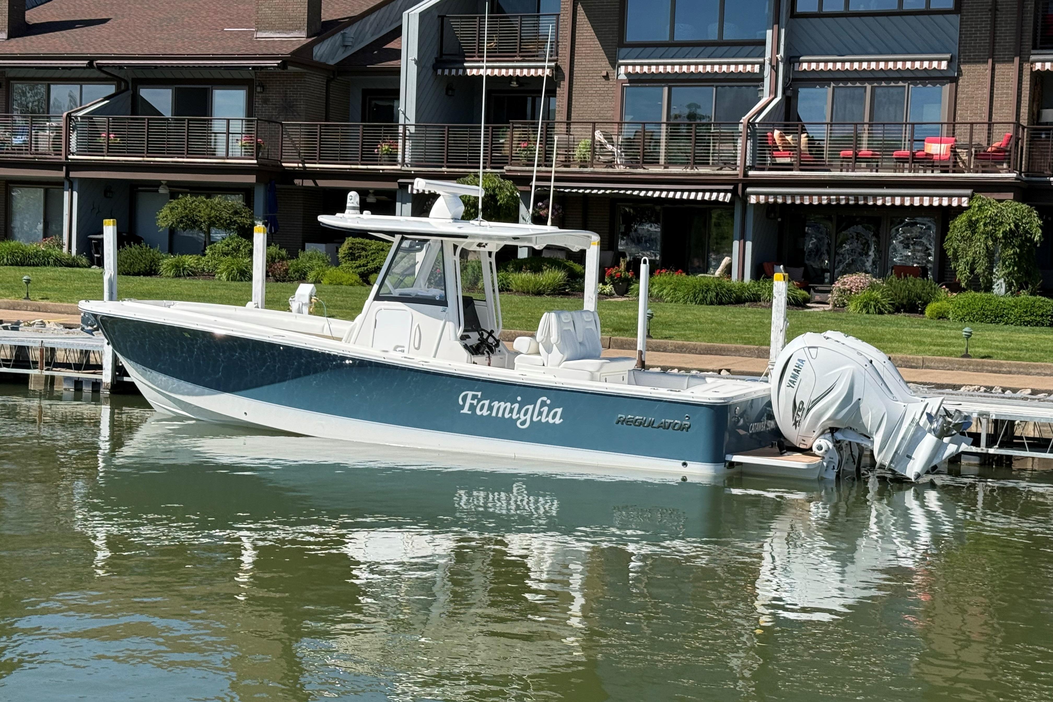 2021 Regulator 31 boat docked by waterfront homes, featuring twin Yamaha engines.