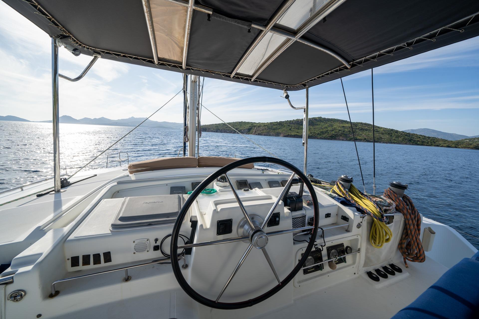 Helm of 2005 Lagoon 440 catamaran with scenic ocean view and clear skies.