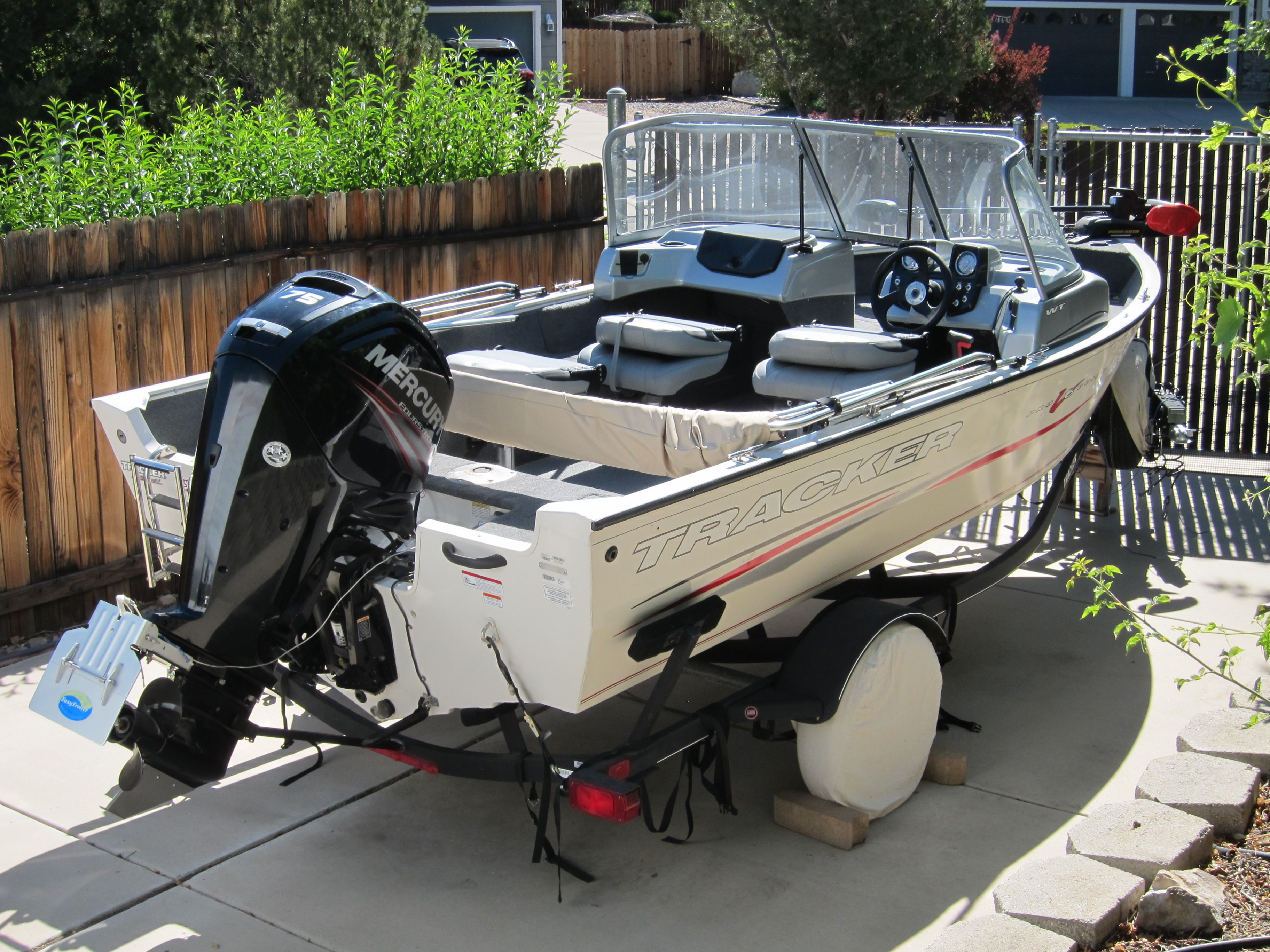 A 2018 Tracker Pro Guide V-16 WT boat on a trailer in a yard.