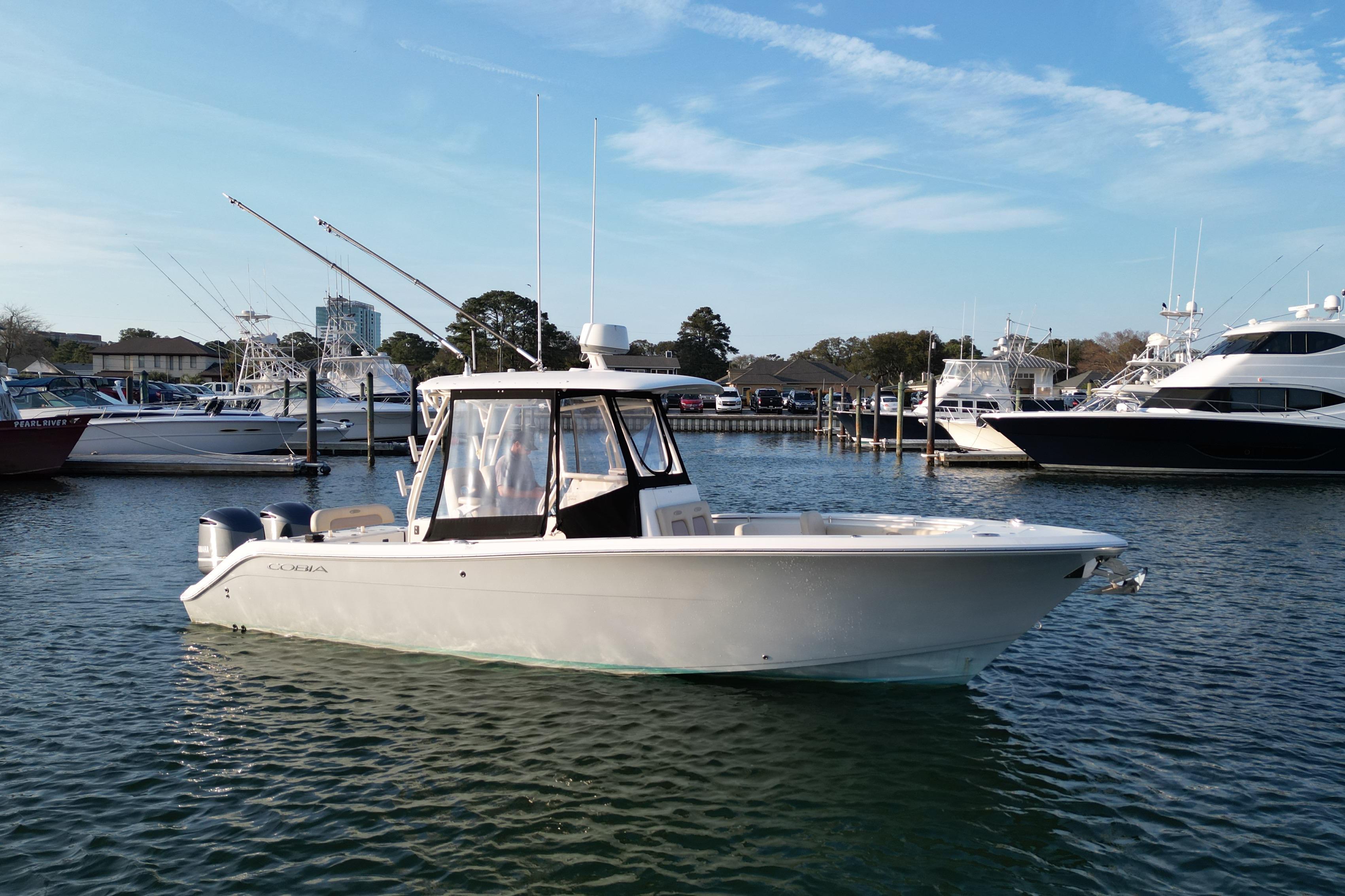 2016 Cobia 296 Center Console boat docked in marina, clear sky background.