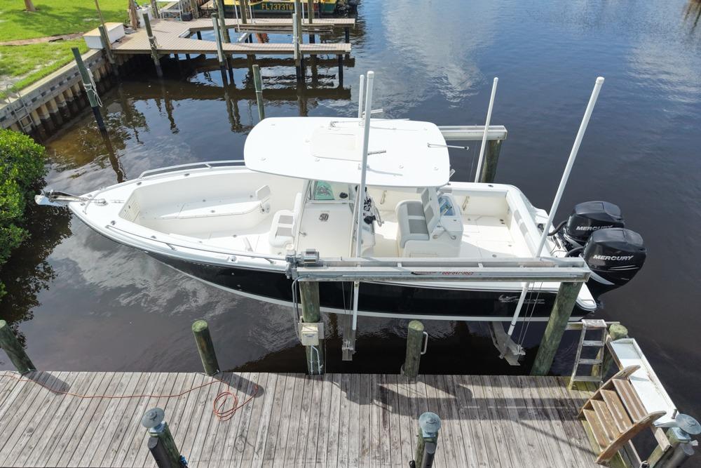 2018 Mako 284 Center Console boat docked by a wooden pier.