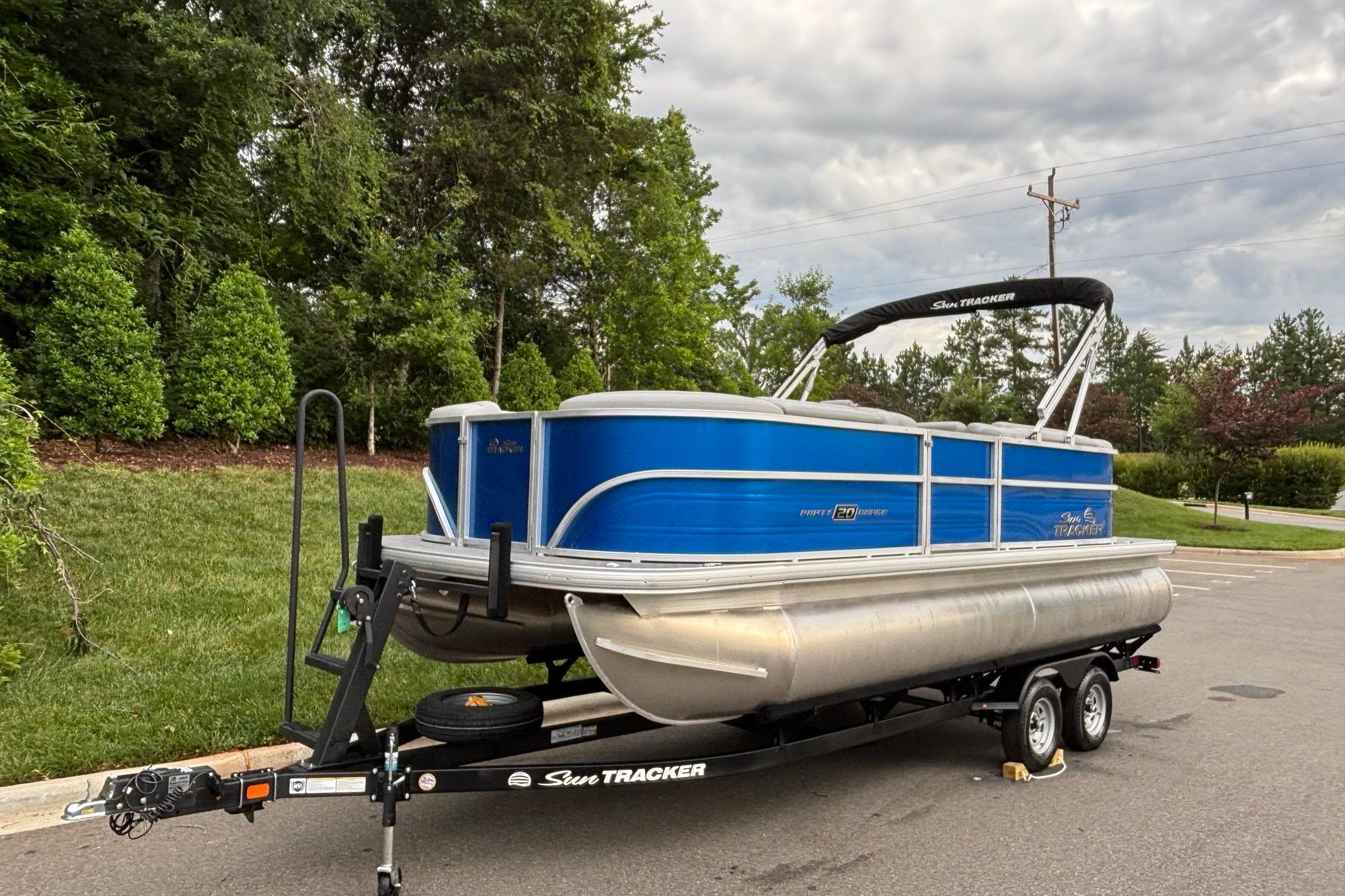 2026 Sun Tracker Party Barge 20 DLX pontoon boat on trailer, parked outdoors.