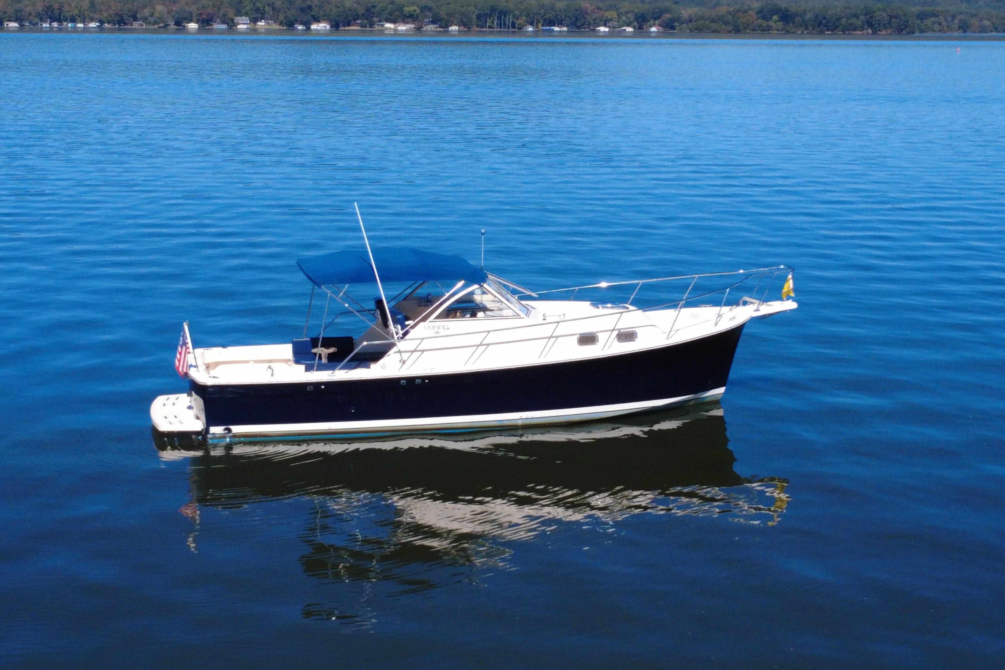 2003 Mainship Pilot 30-II boat on calm blue water with canopy.