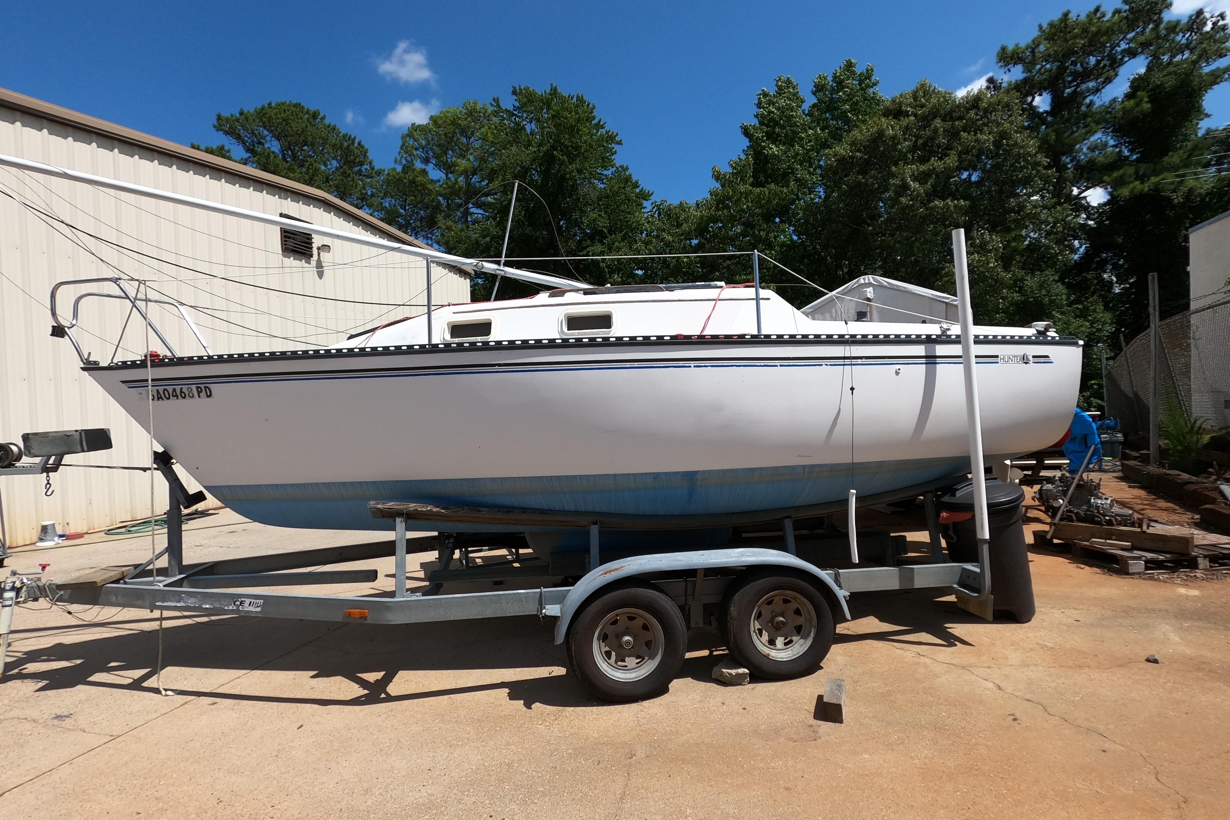 1984 Hunter 22 sailboat on trailer, parked outdoors near a building, under a clear blue sky.