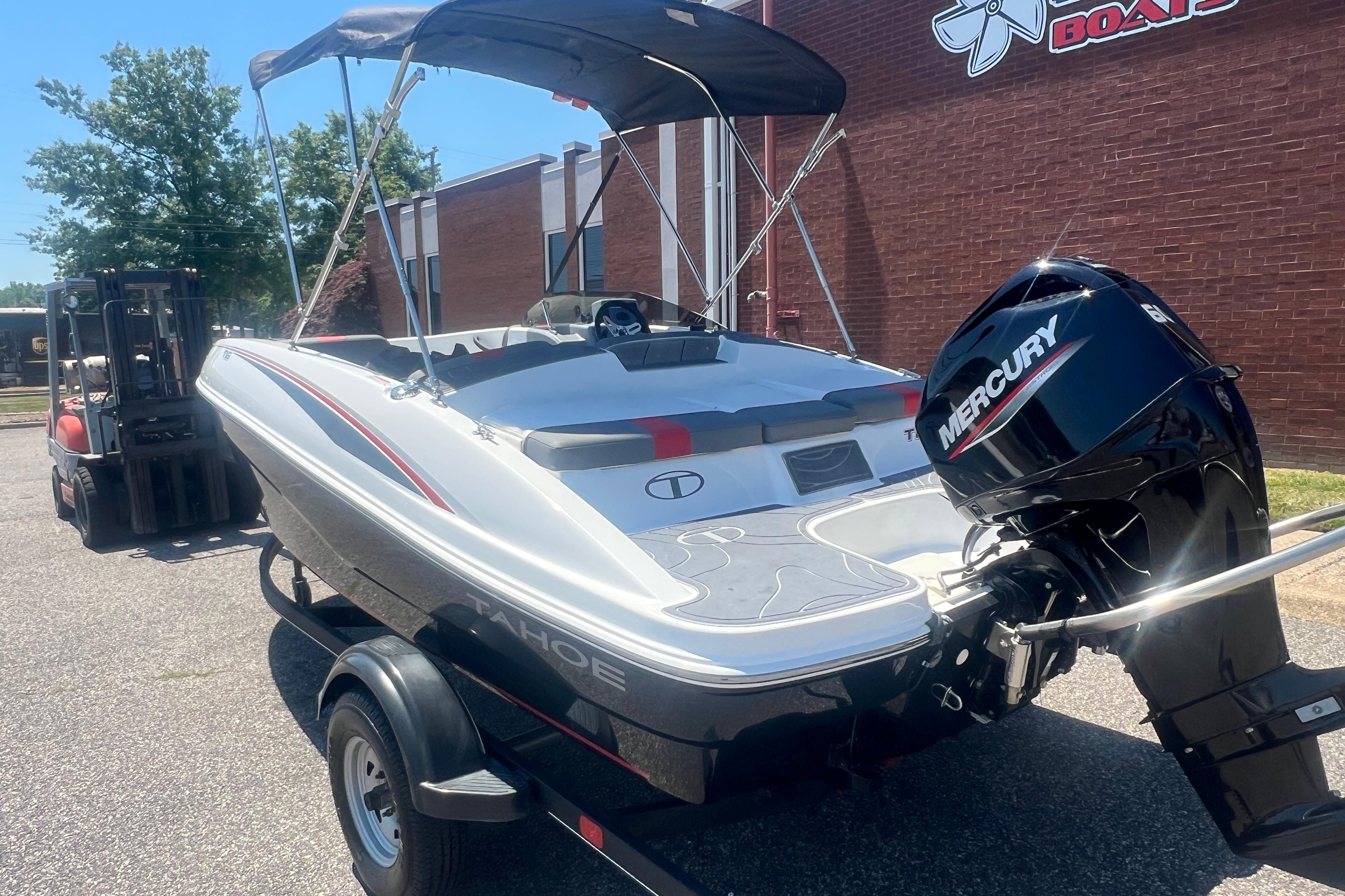 2023 Tahoe T16 boat with Mercury engine on trailer, parked outdoors.